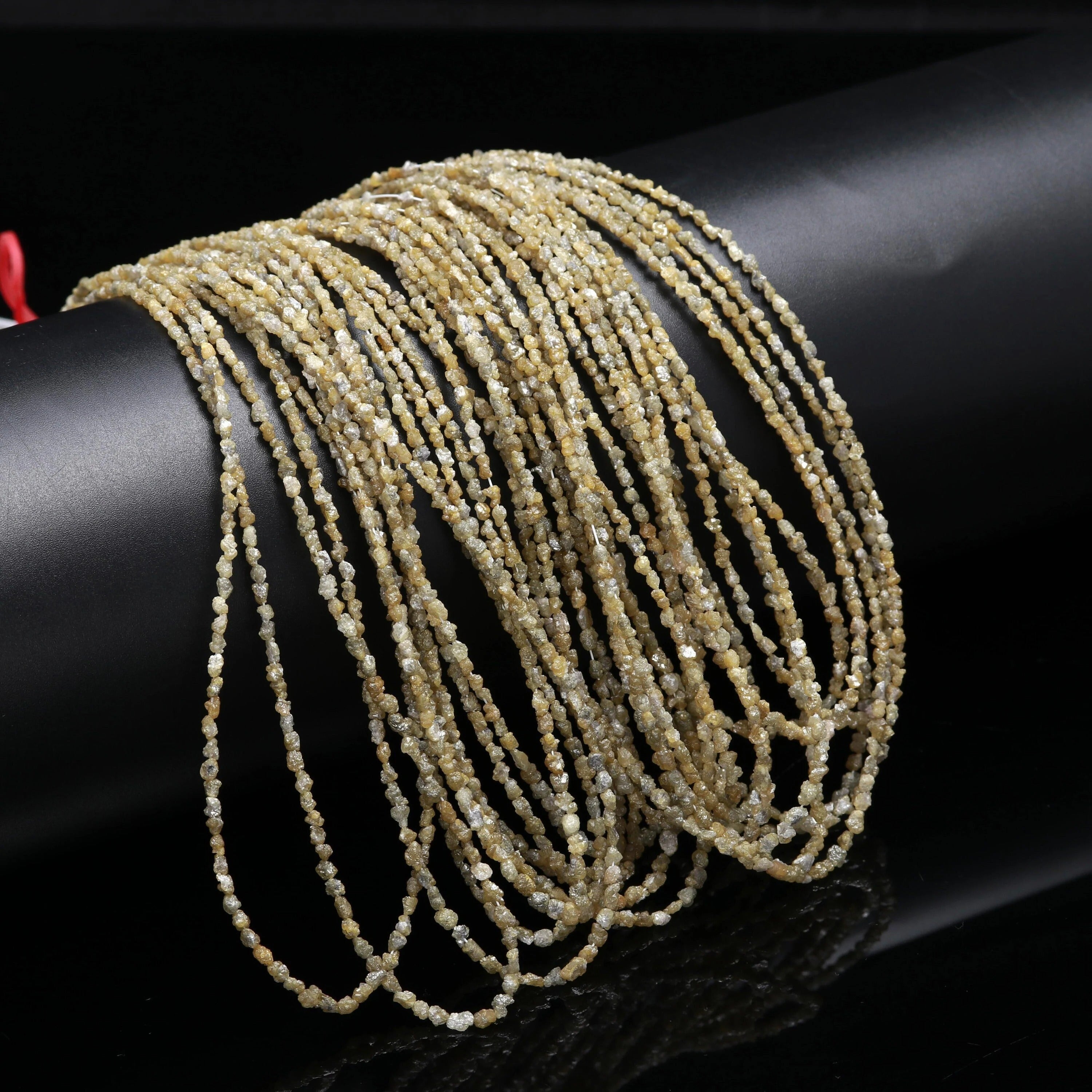 Multiple strands of light-colored beaded necklace on a dark surface