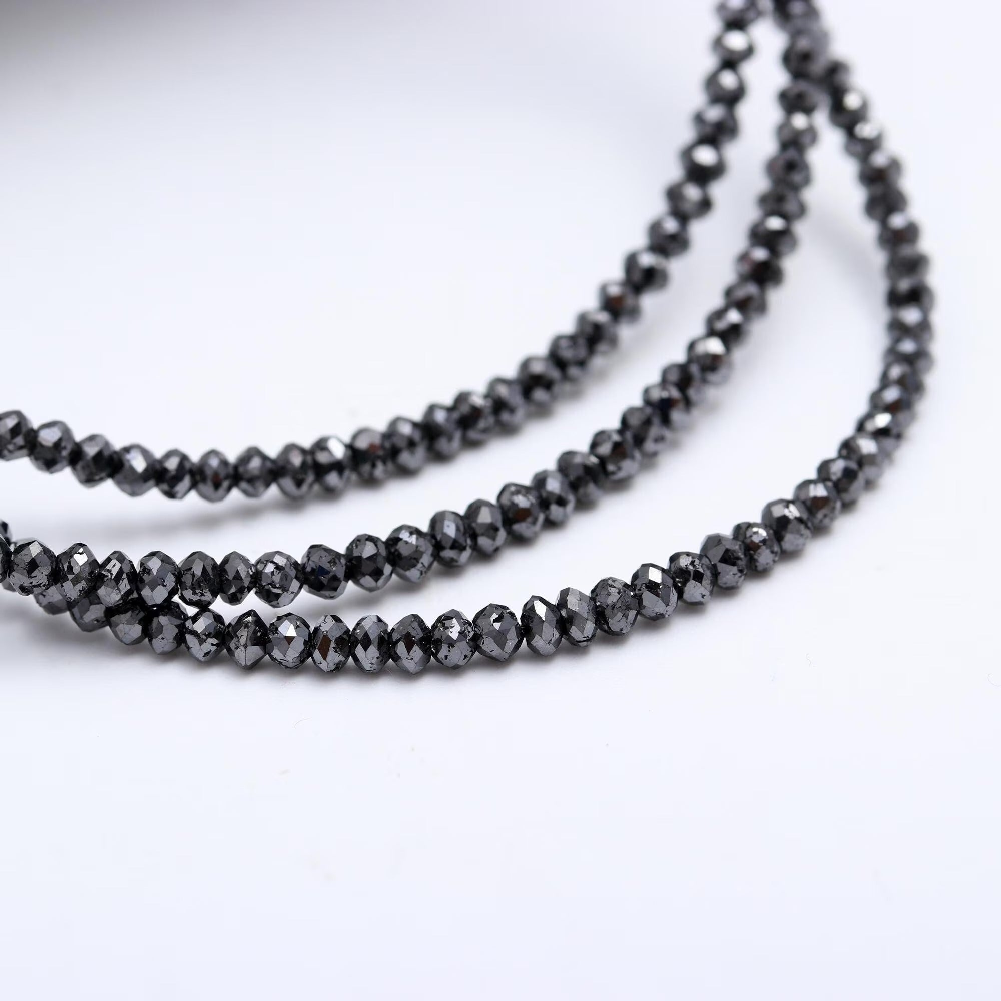 Two strands of black beaded necklace on a white background