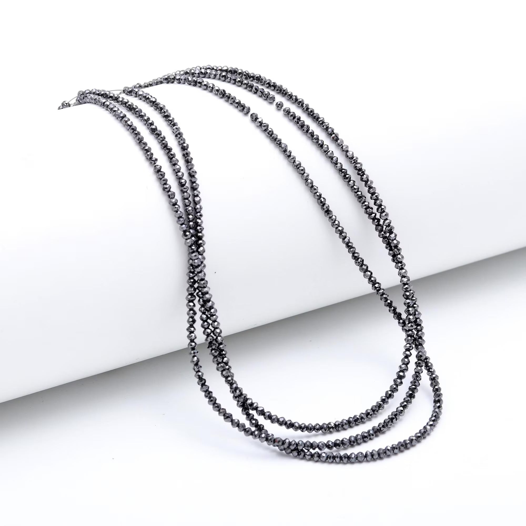 Multiple black beaded necklaces on a white surface
