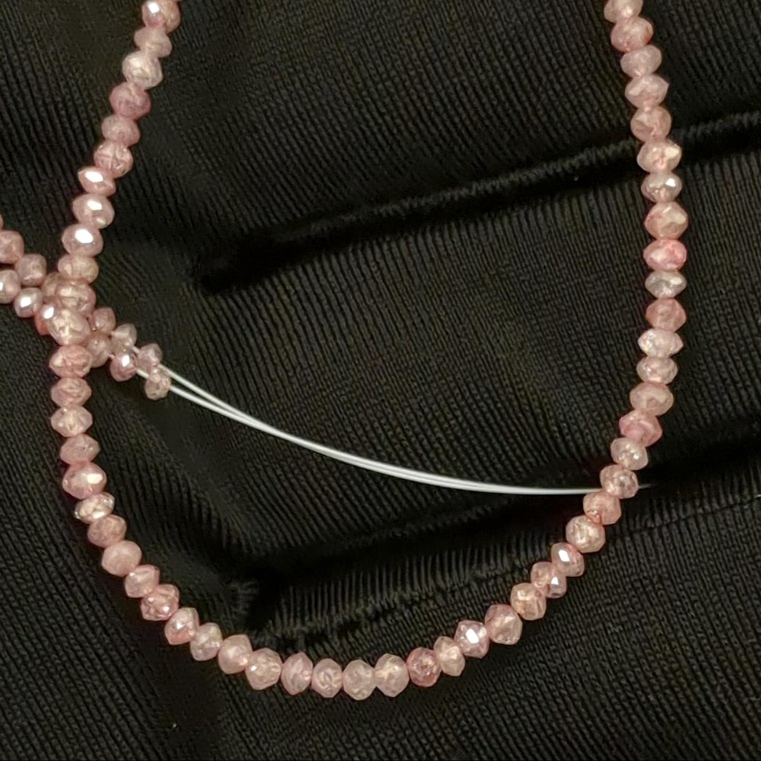Pink beaded necklace on a black fabric background
