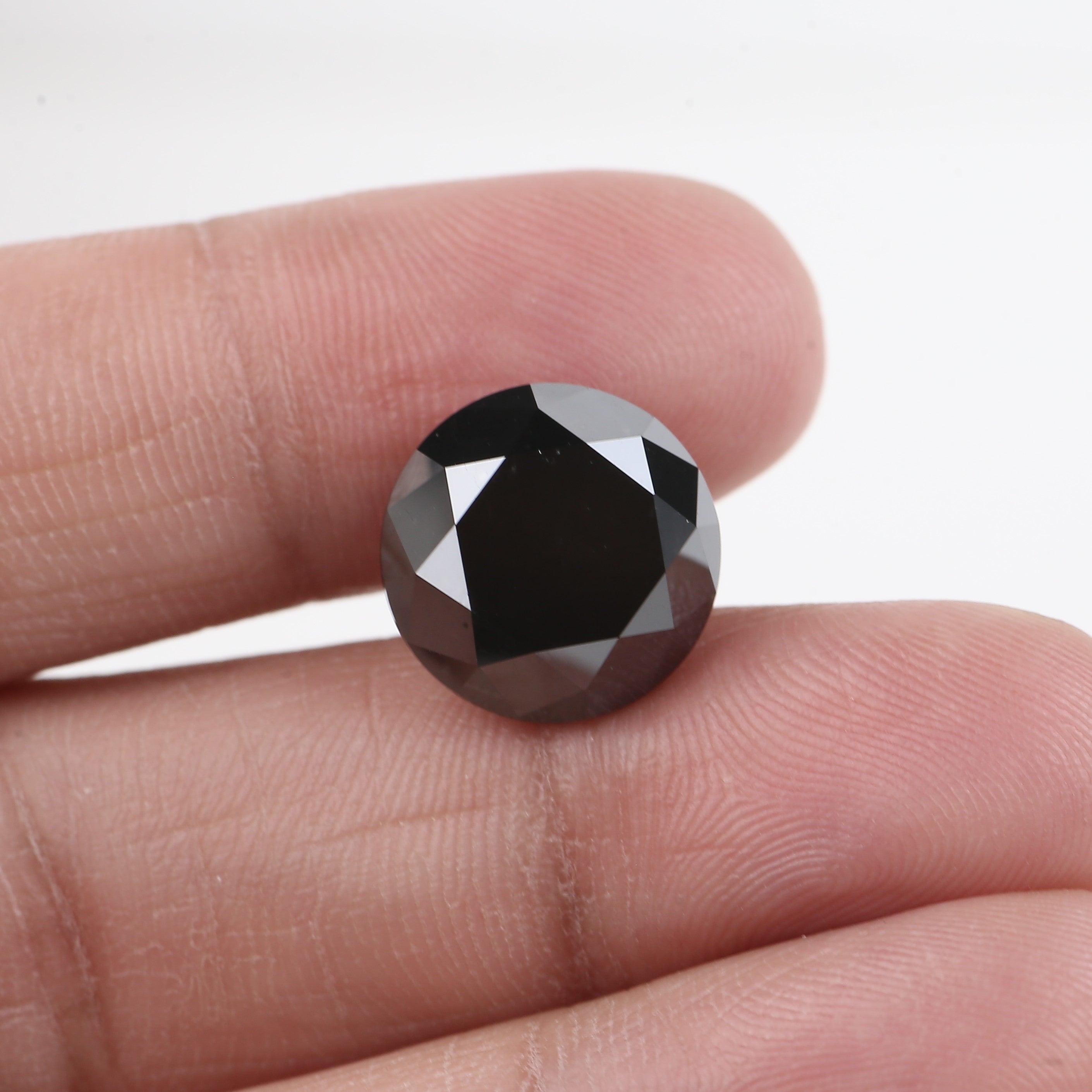 Black diamond held between fingers against a white background