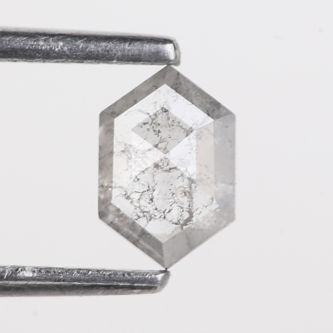 Hexagonal crystal with metallic sheen on a light gray background