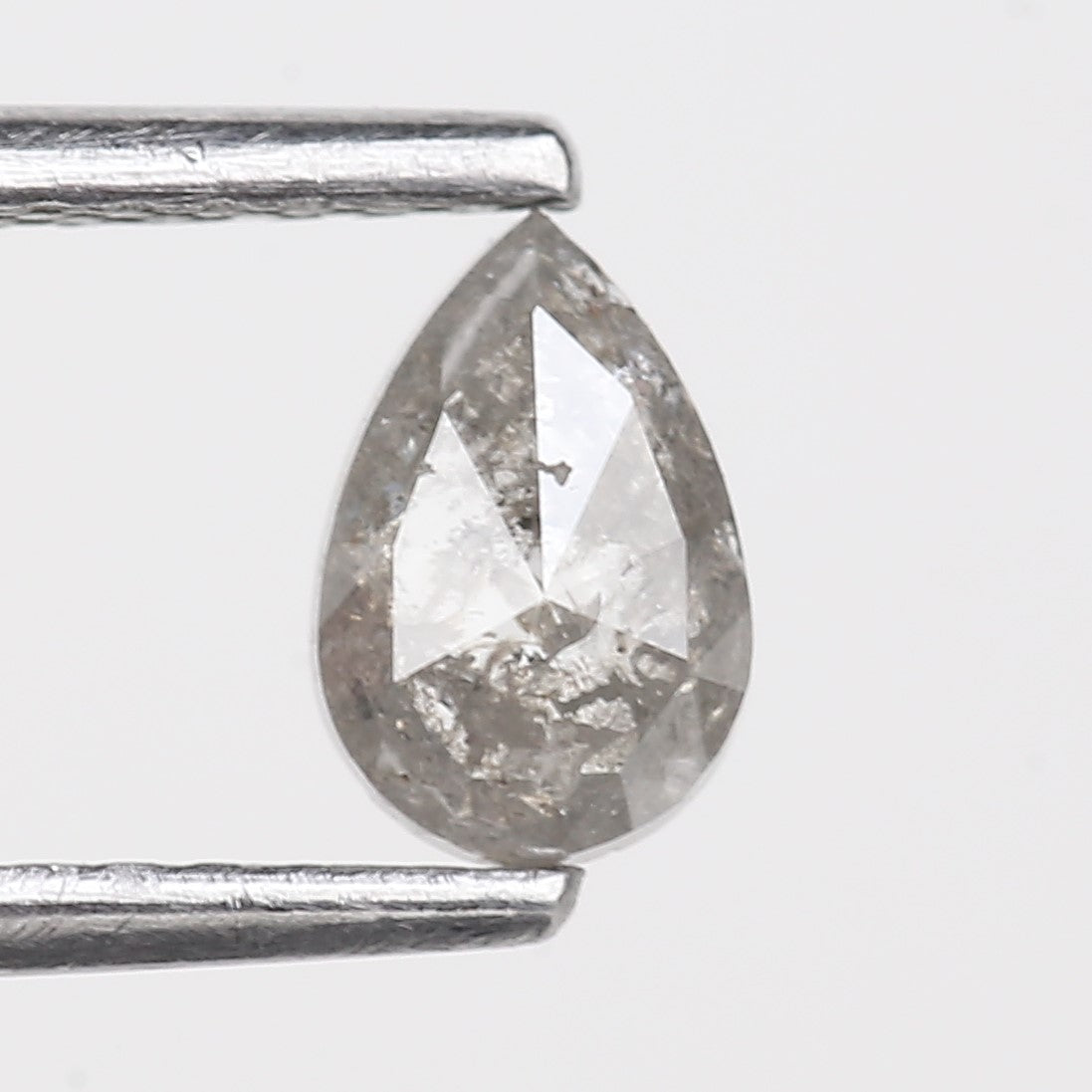 Teardrop-shaped diamond held between two metal prongs on a light gray background