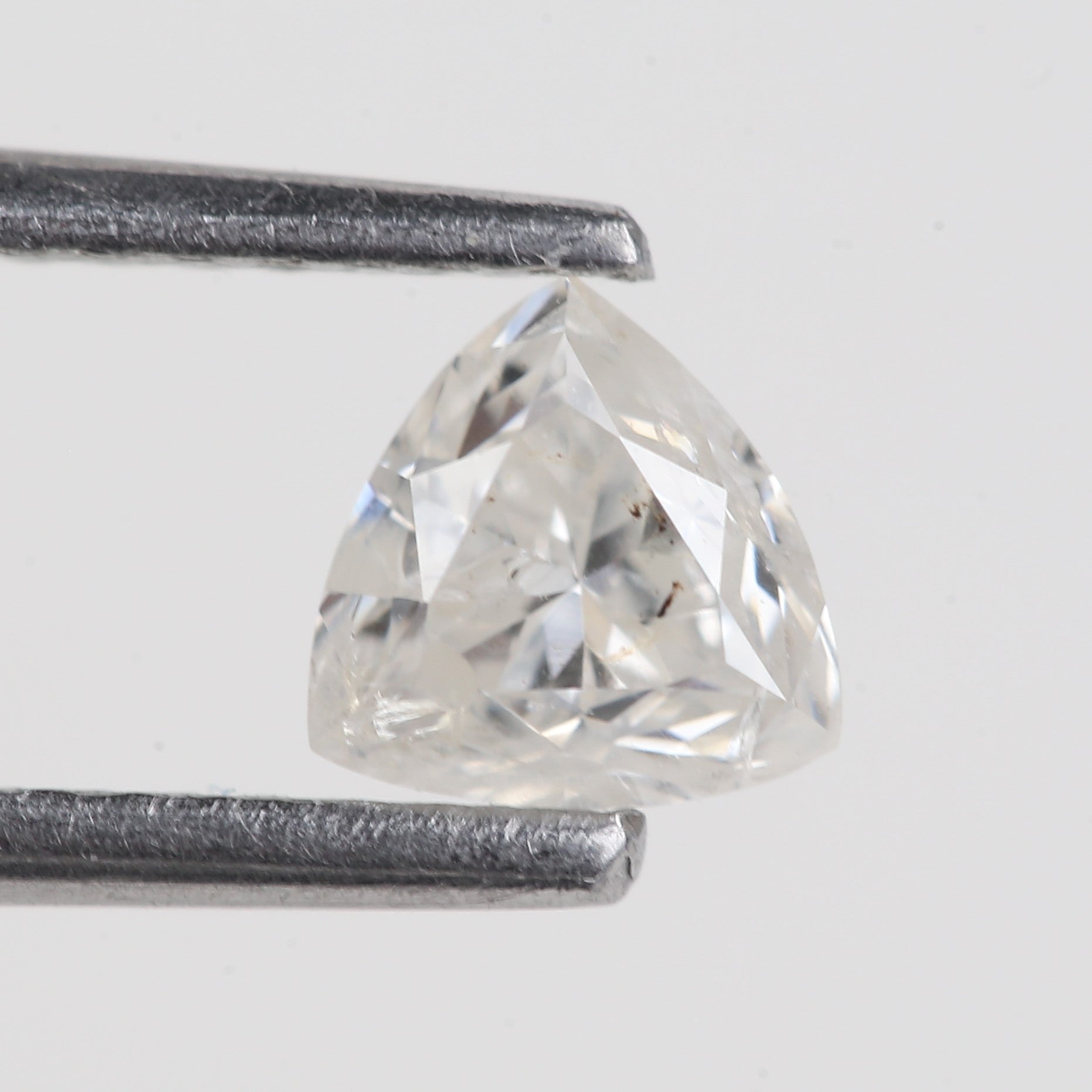 Trillion-cut diamond next to a ruler on a light gray background