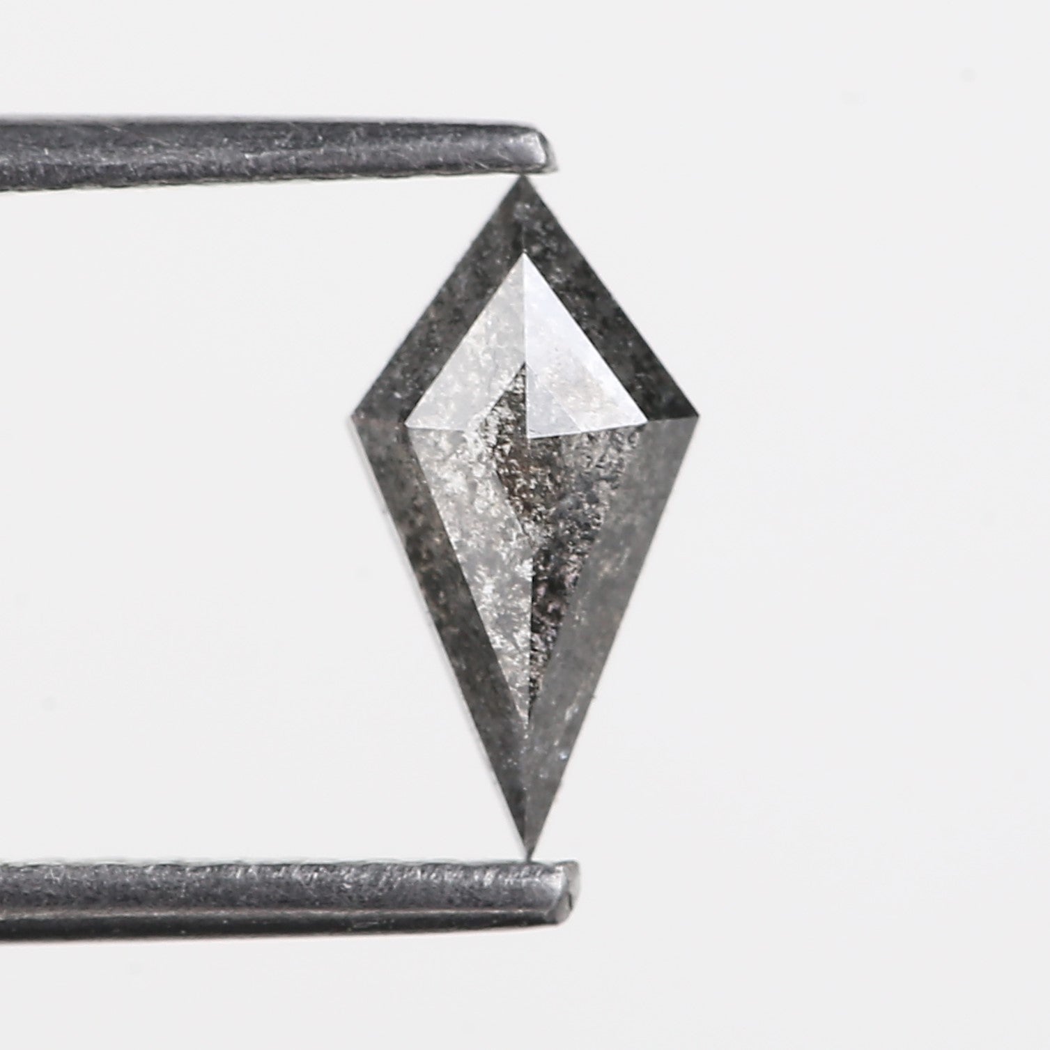 Diamond held between two metal prongs on a light gray background