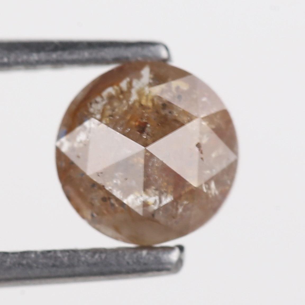 Brown diamond held by tweezers on a white background