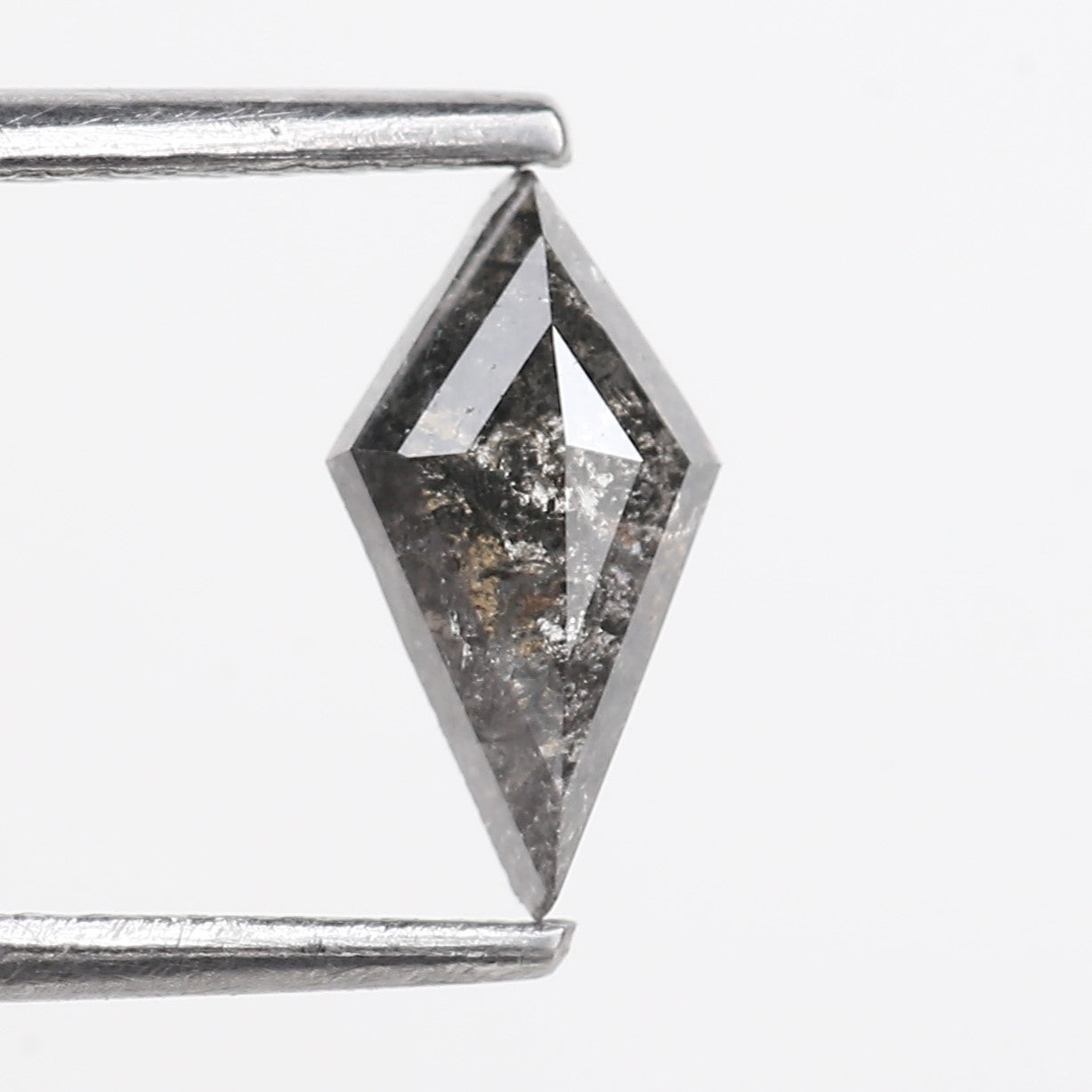 Faceted gemstone held between two metal prongs on a white background
