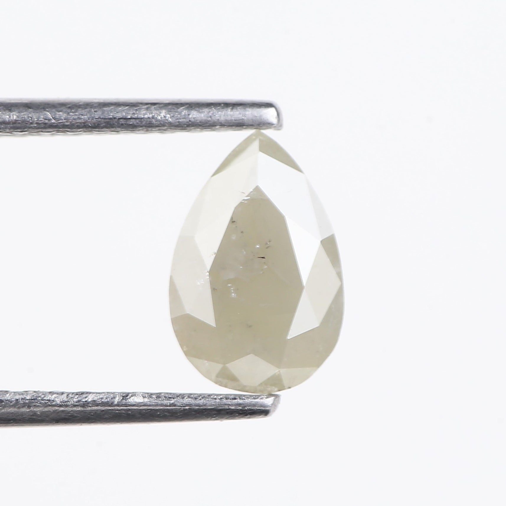 Teardrop-shaped gemstone held by tweezers on a white background