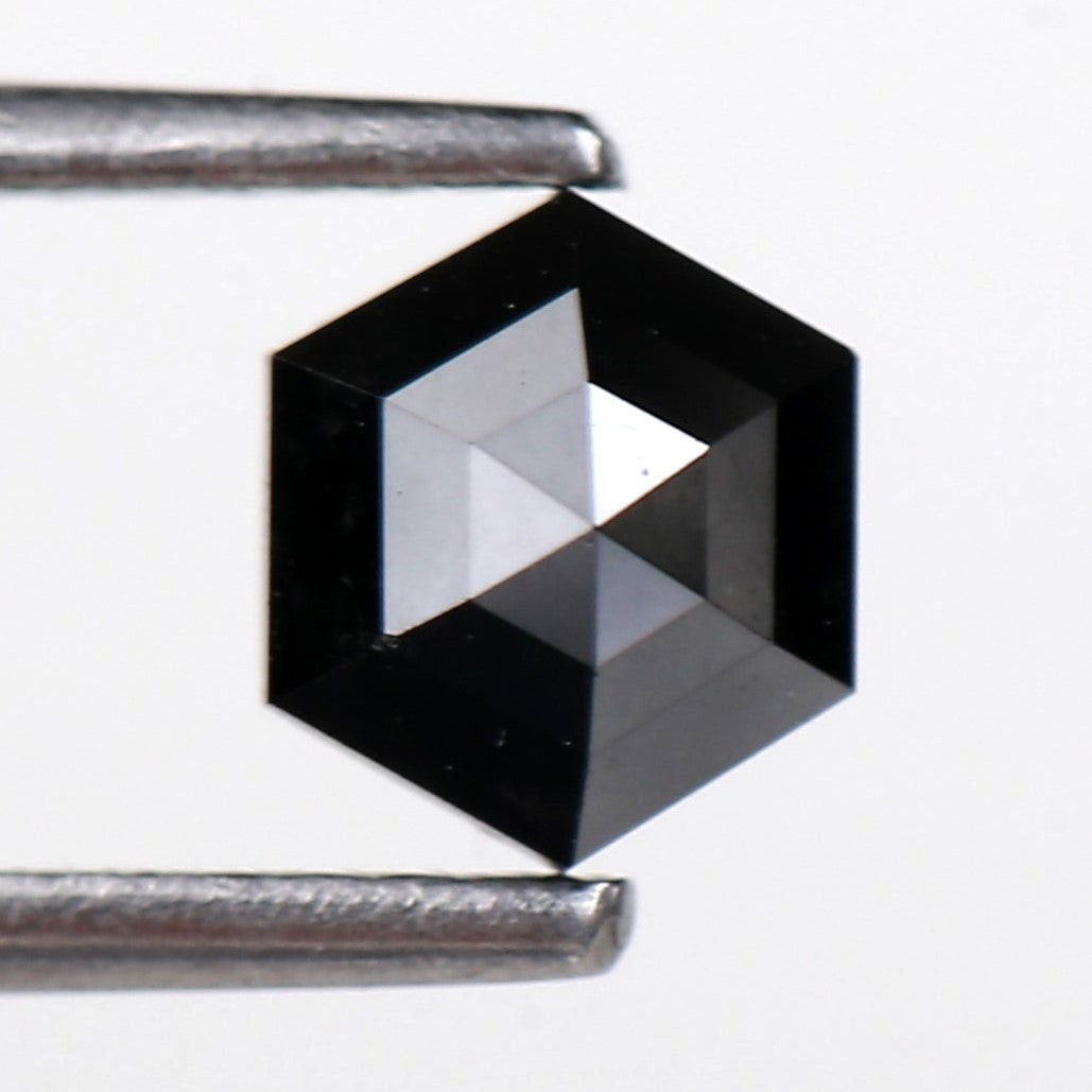 Hexagon Black diamond held between tweezers on a white background