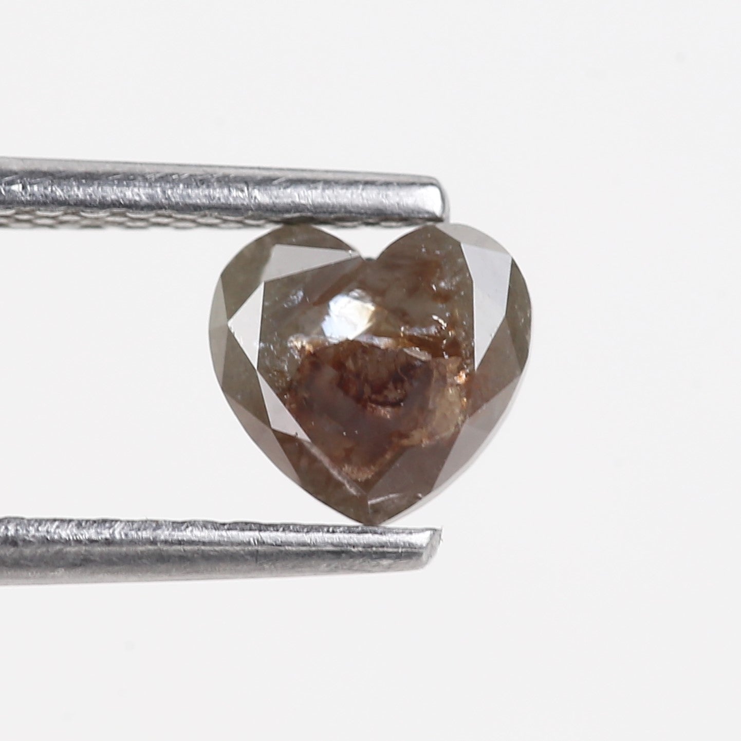Heart-shaped brown diamond held between two silver prongs on a white background
