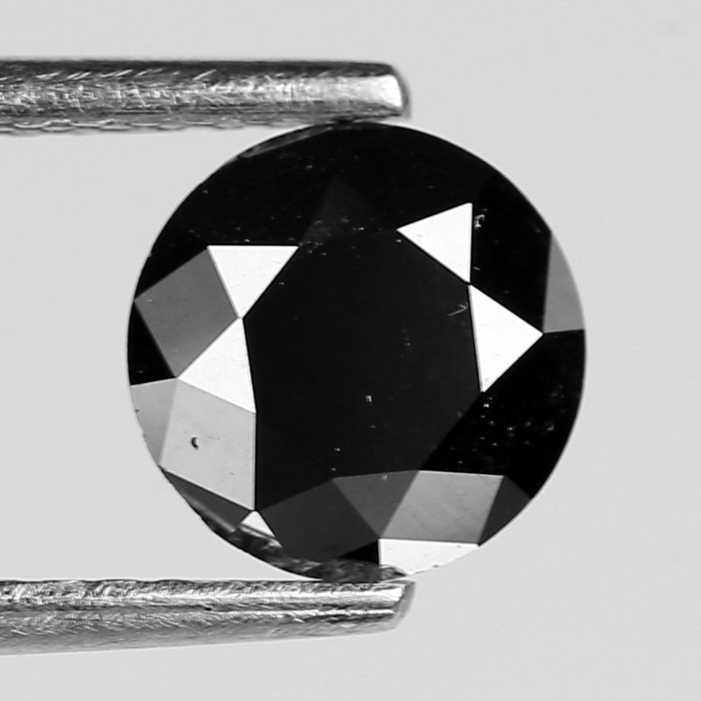 Round black diamond held between two tweezers on a light gray background