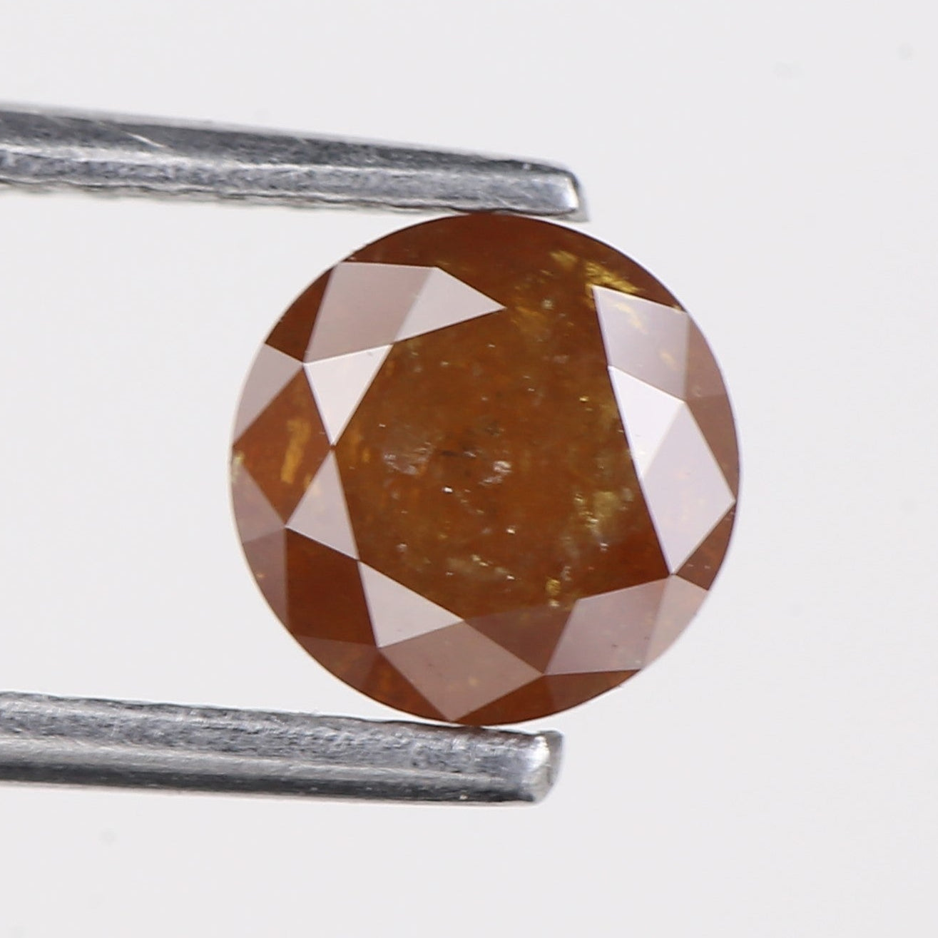 ORANGE diamond held between two silver prongs on a white background