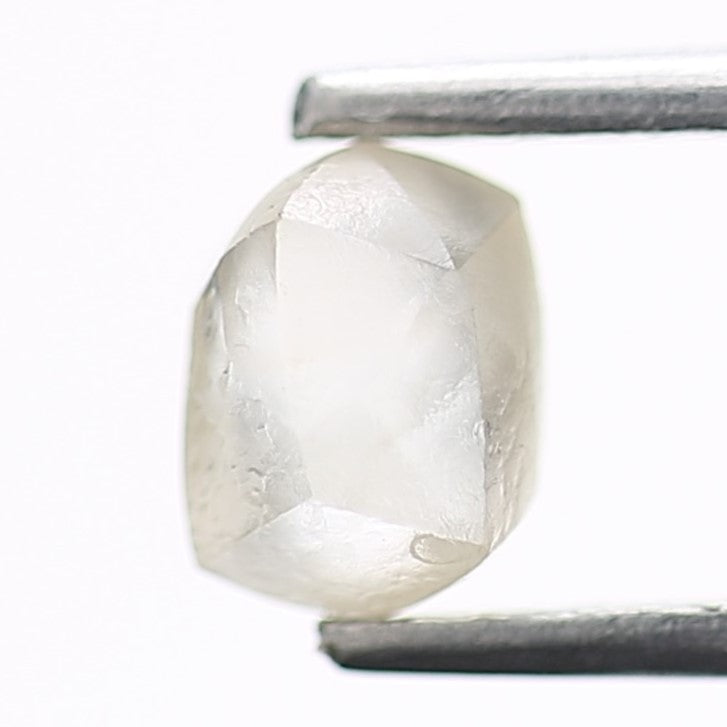 Raw diamond held by tweezers on a white background