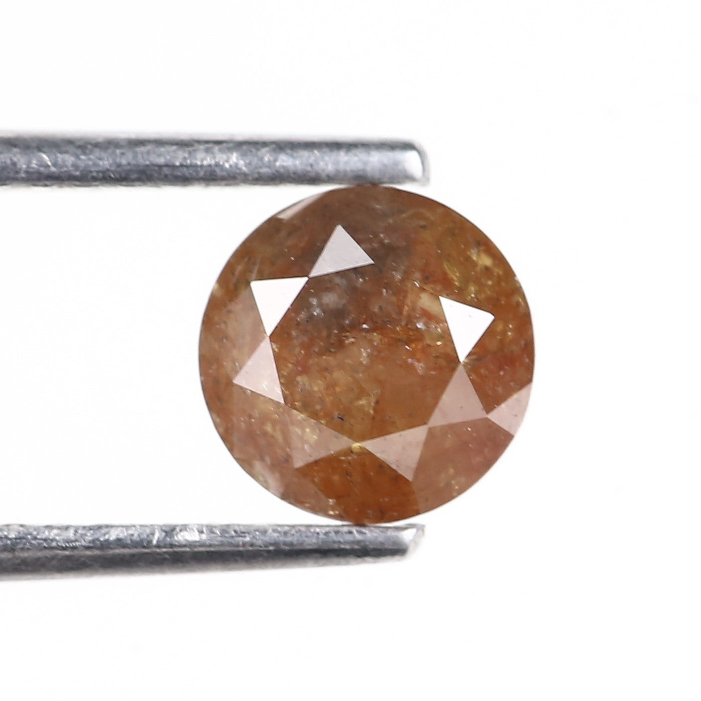 Brown gemstone held by tweezers on a white background