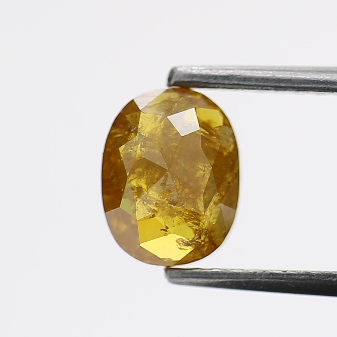 Yellow diamond held by tweezers on a white background