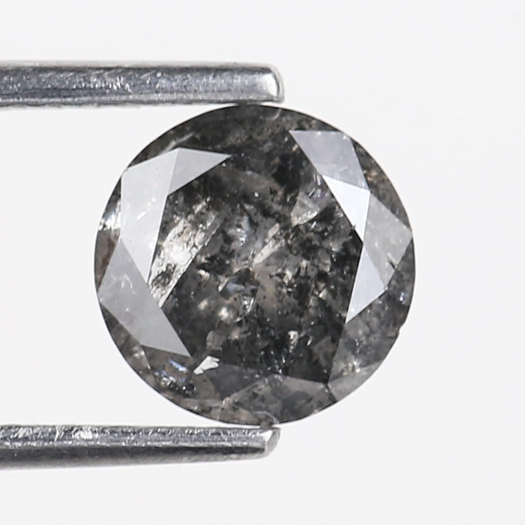 Round cut diamond held between two metal prongs on a white background