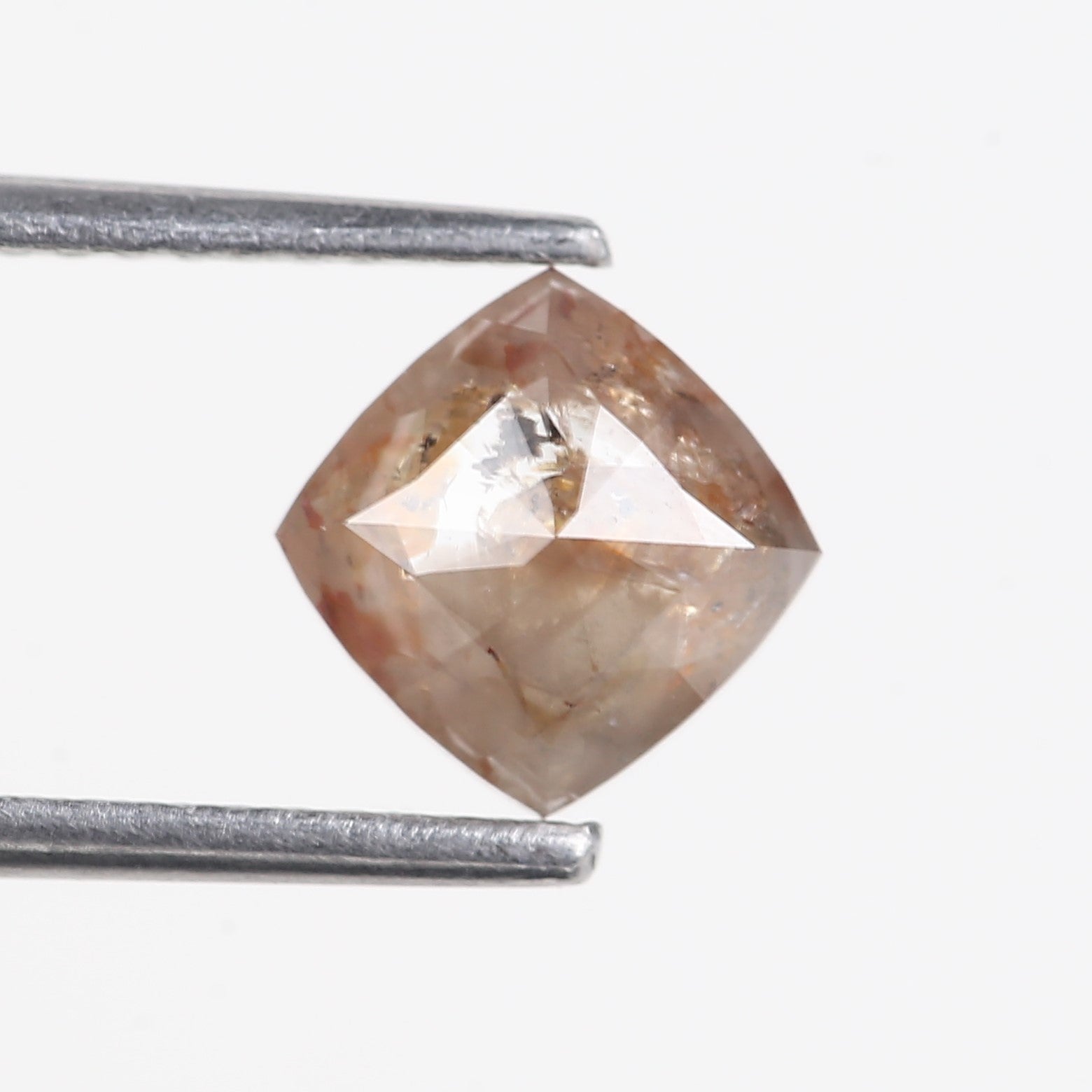 Brown diamond held between two silver prongs against a white background