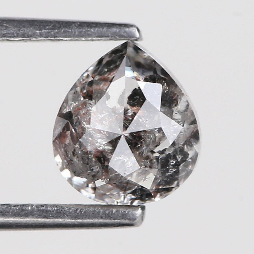 Faceted Pear held between tweezers on a light gray background