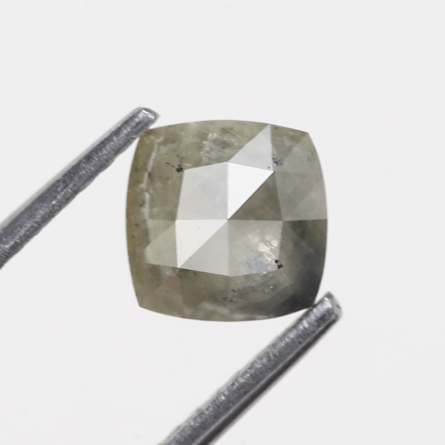 Cushion-shaped diamond with a ruler for scale on a white background