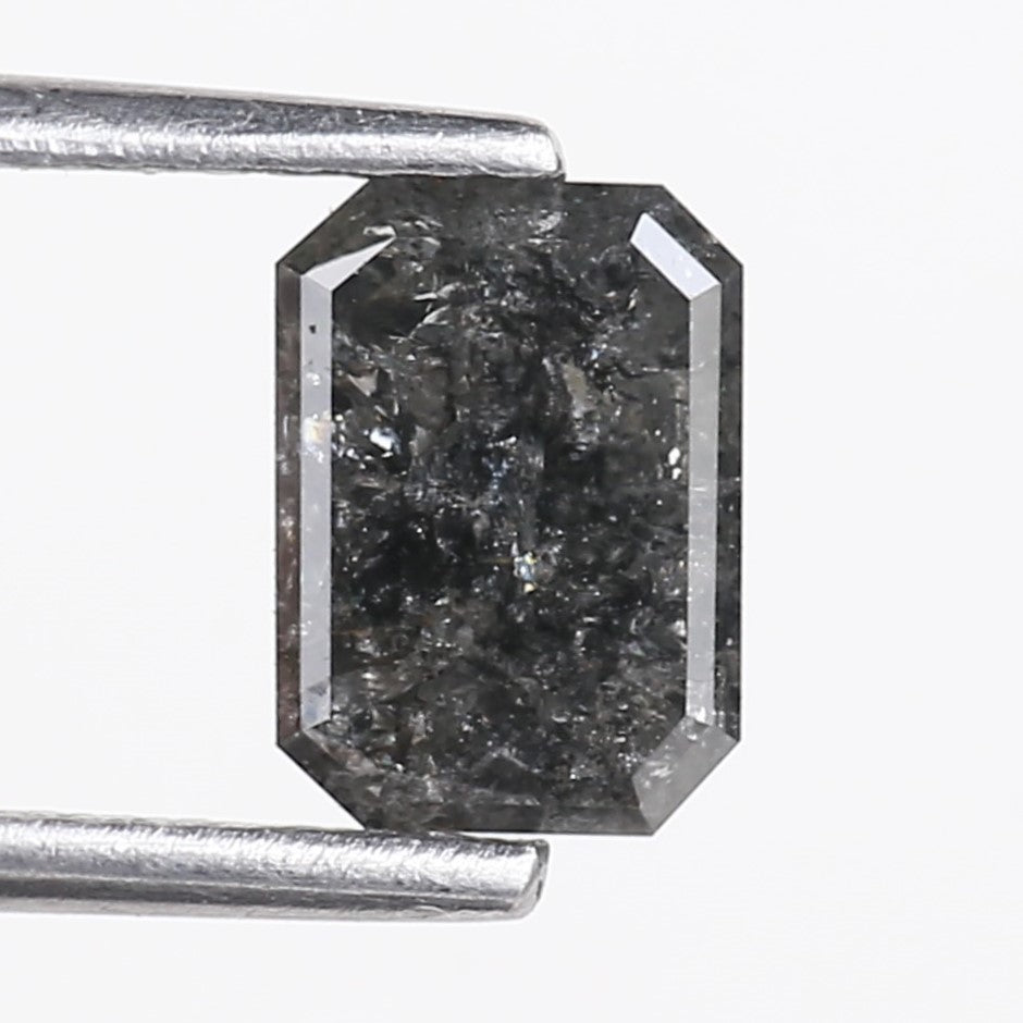 Emerald black diamond held by tweezers on a white background