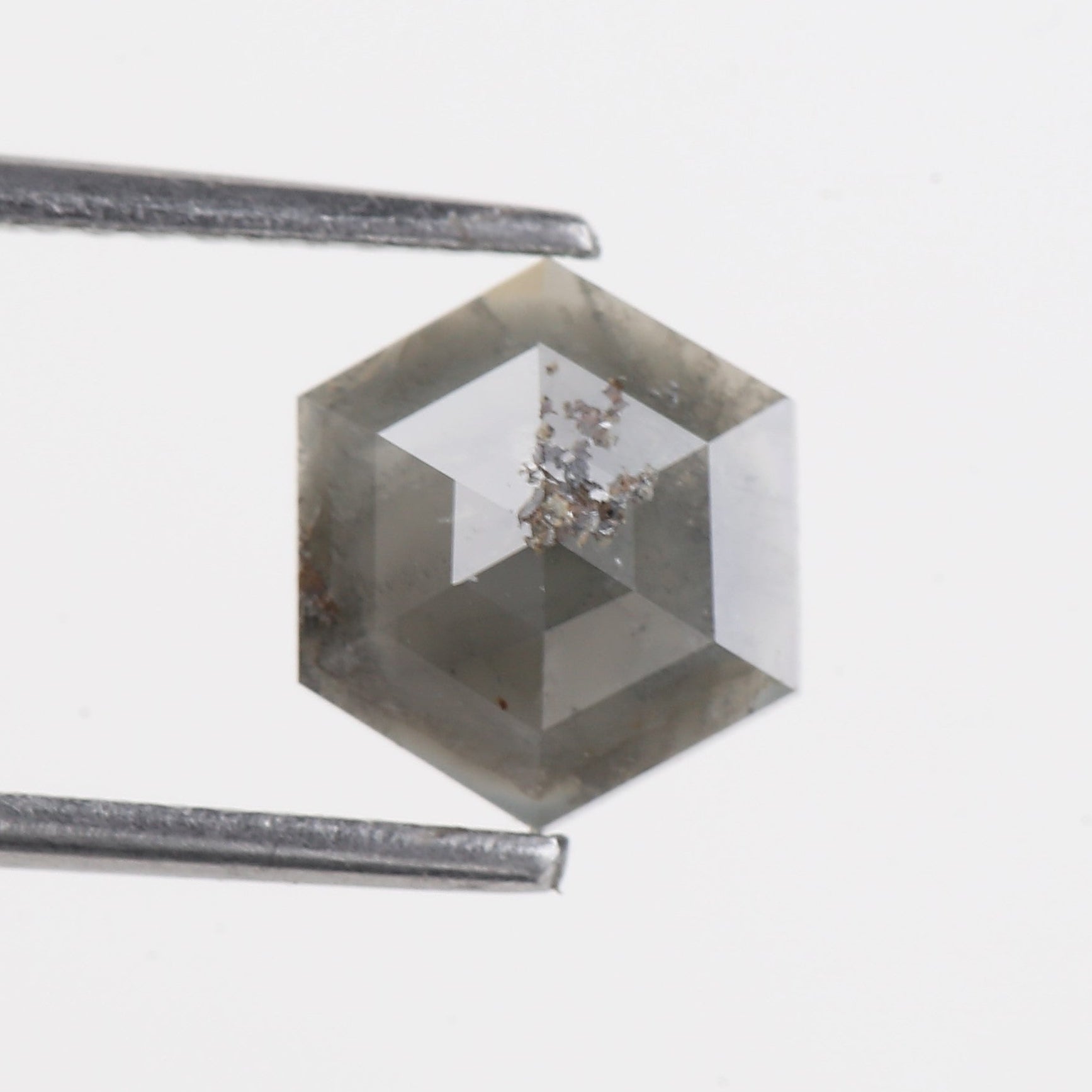 Hexagonal crystal held by tweezers on a light gray background
