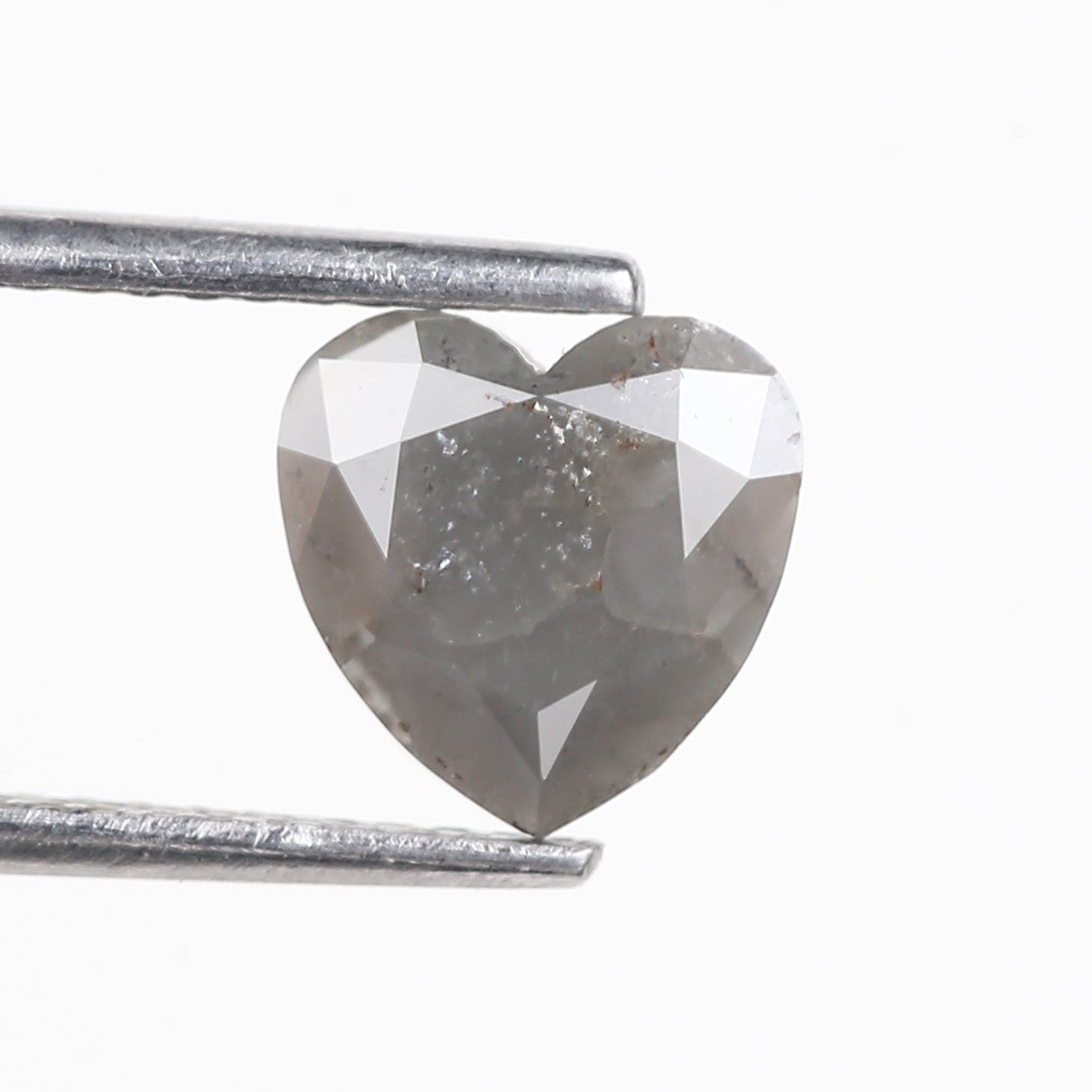 Heart-shaped diamond held between tweezers on a white background