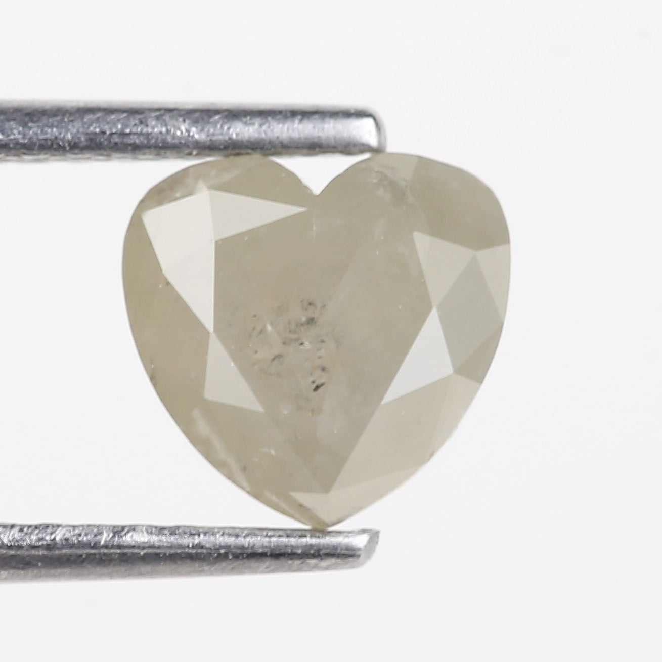 Heart-shaped diamond held between two metal prongs on a white background