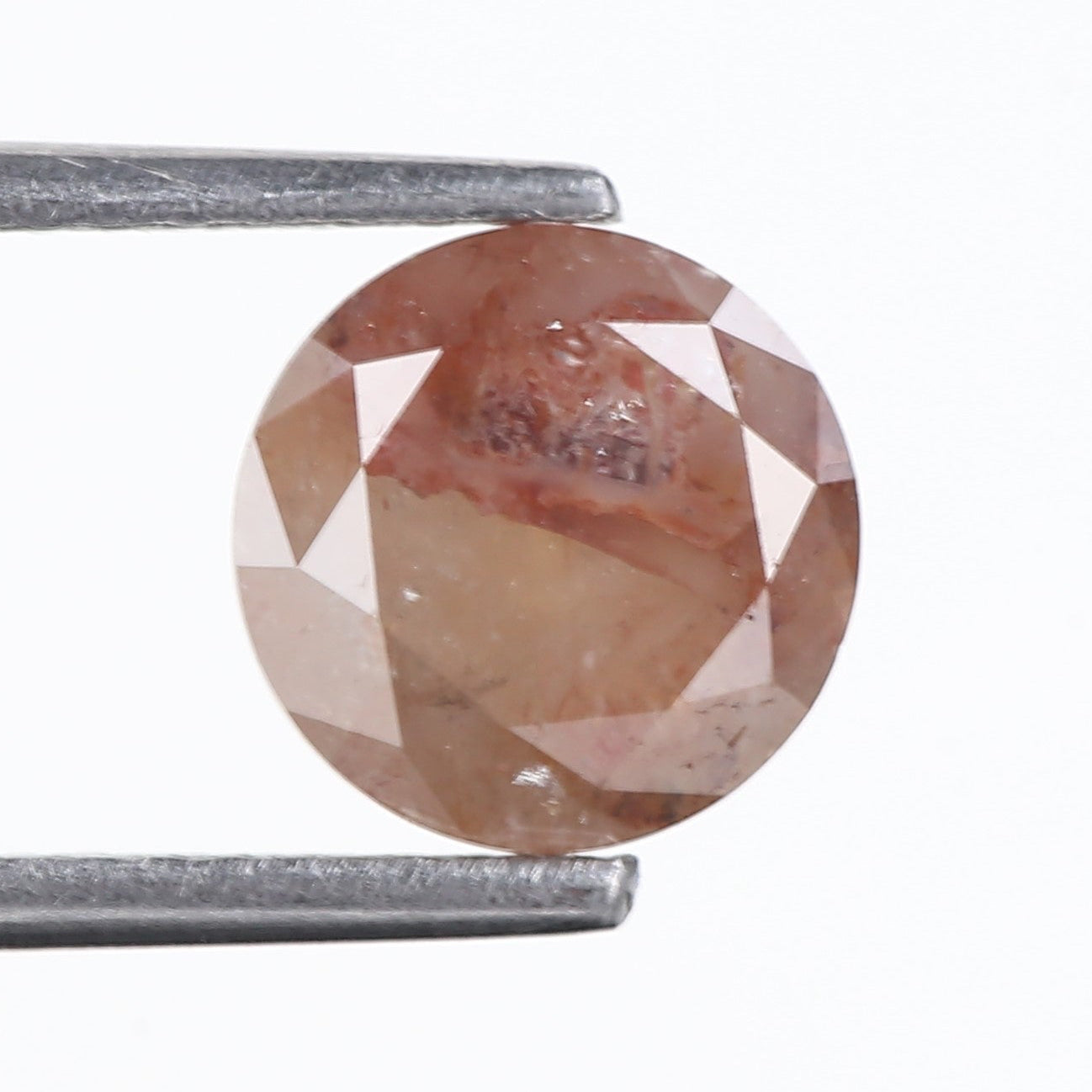 Brown diamond held between two metal prongs on a white background