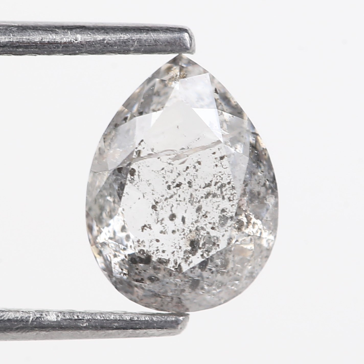 Teardrop-shaped diamond held by tweezers on a white background