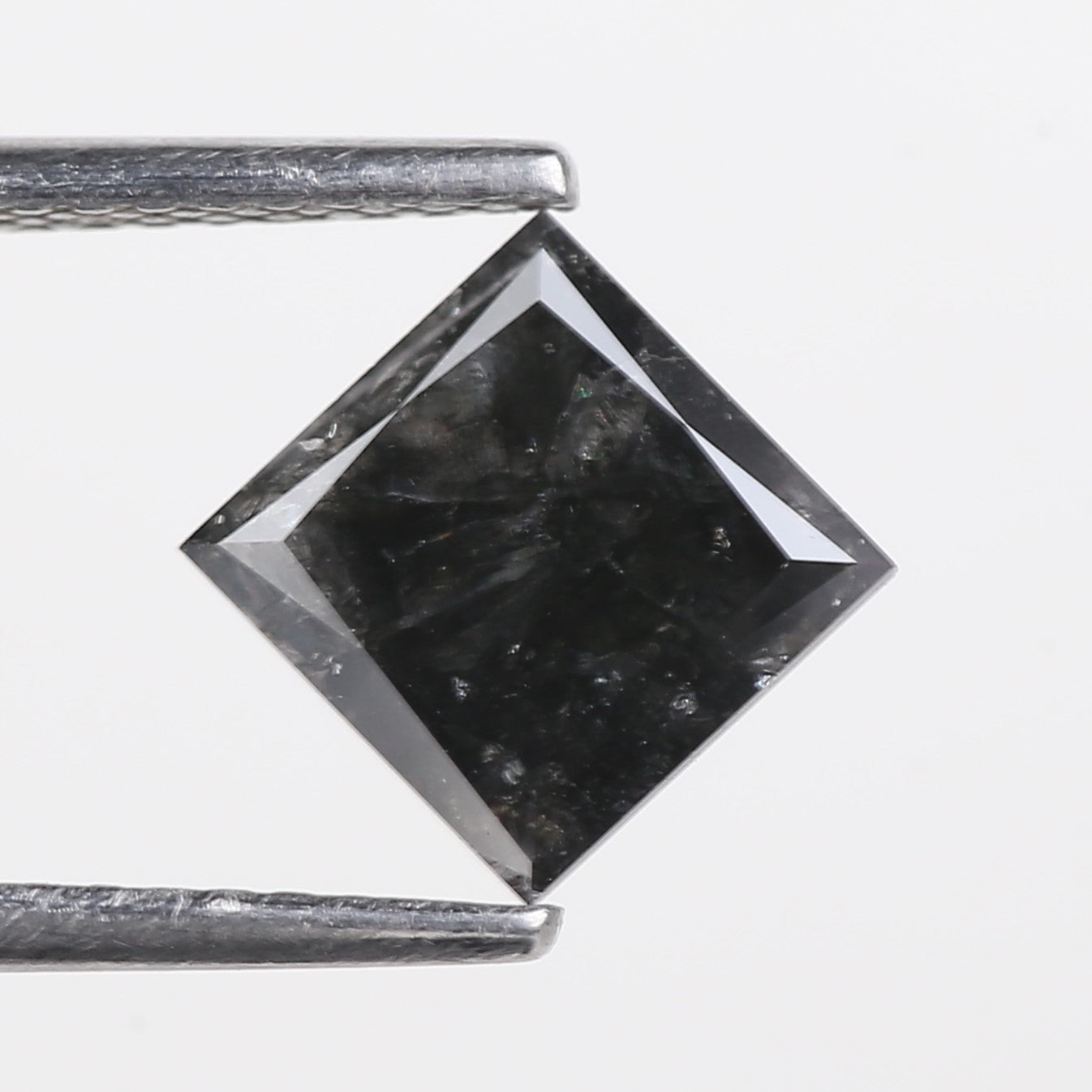 Black diamond with a silver prong setting on a white background