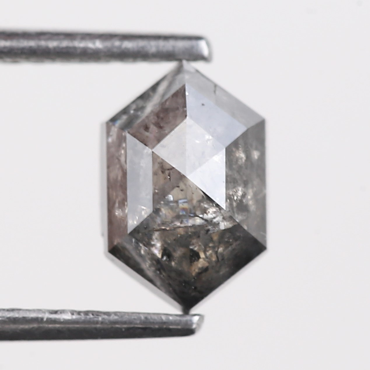 Faceted diamond with a hexagonal shape on a light gray background