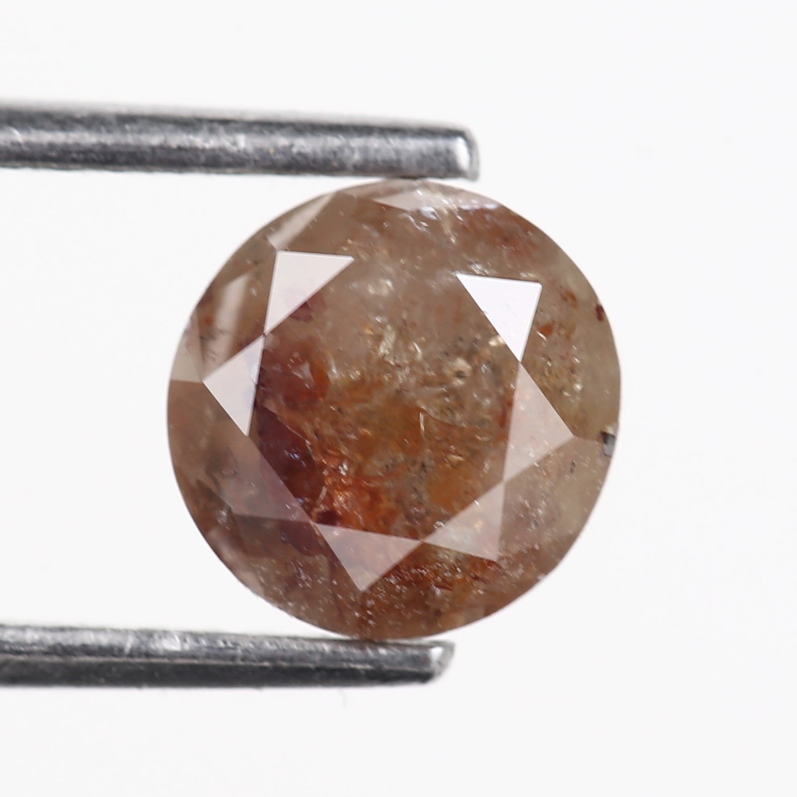 Brown diamond held between two metal sticks on a white background