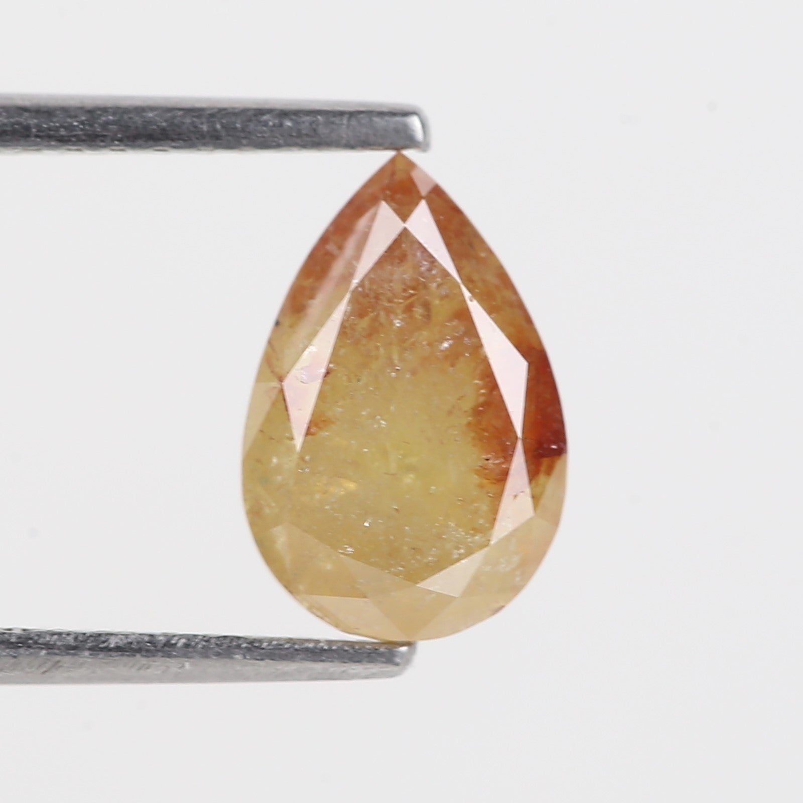 Teardrop-shaped yellowish-brown gemstone held between two metal prongs on a white background