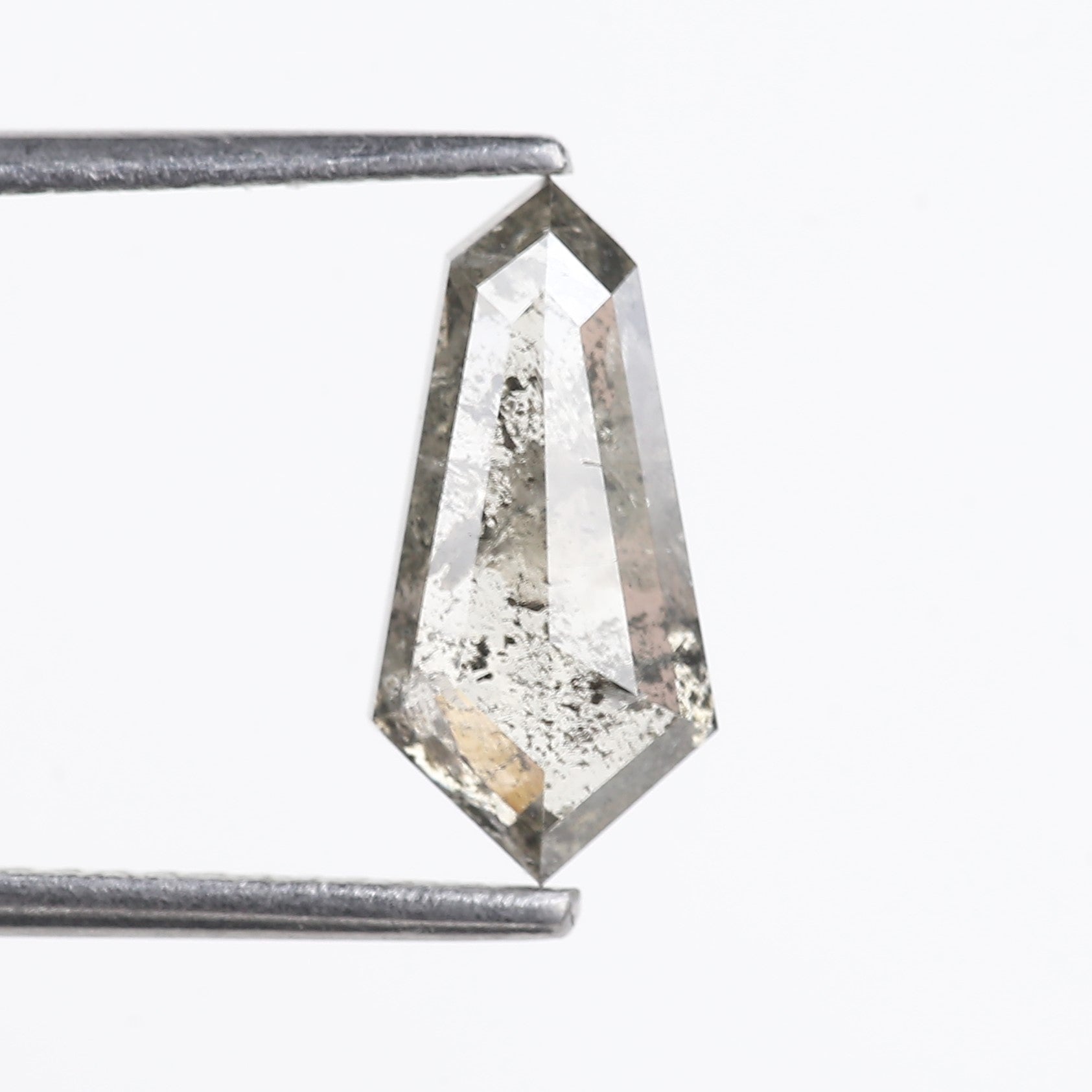 Faceted gemstone held between two metal prongs on a white background