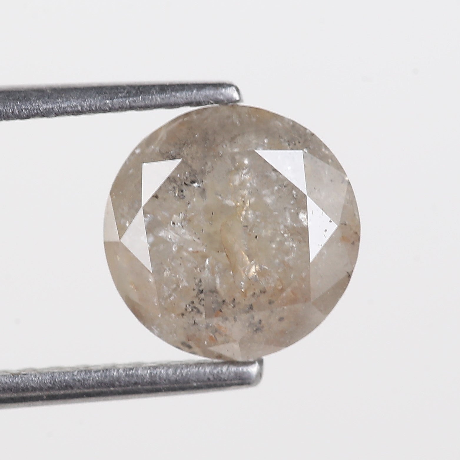 Diamond held between tweezers on a light gray background