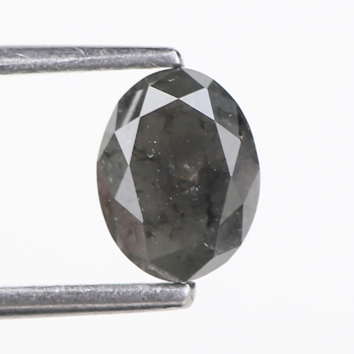 Faceted black diamond held between two metal prongs on a white background