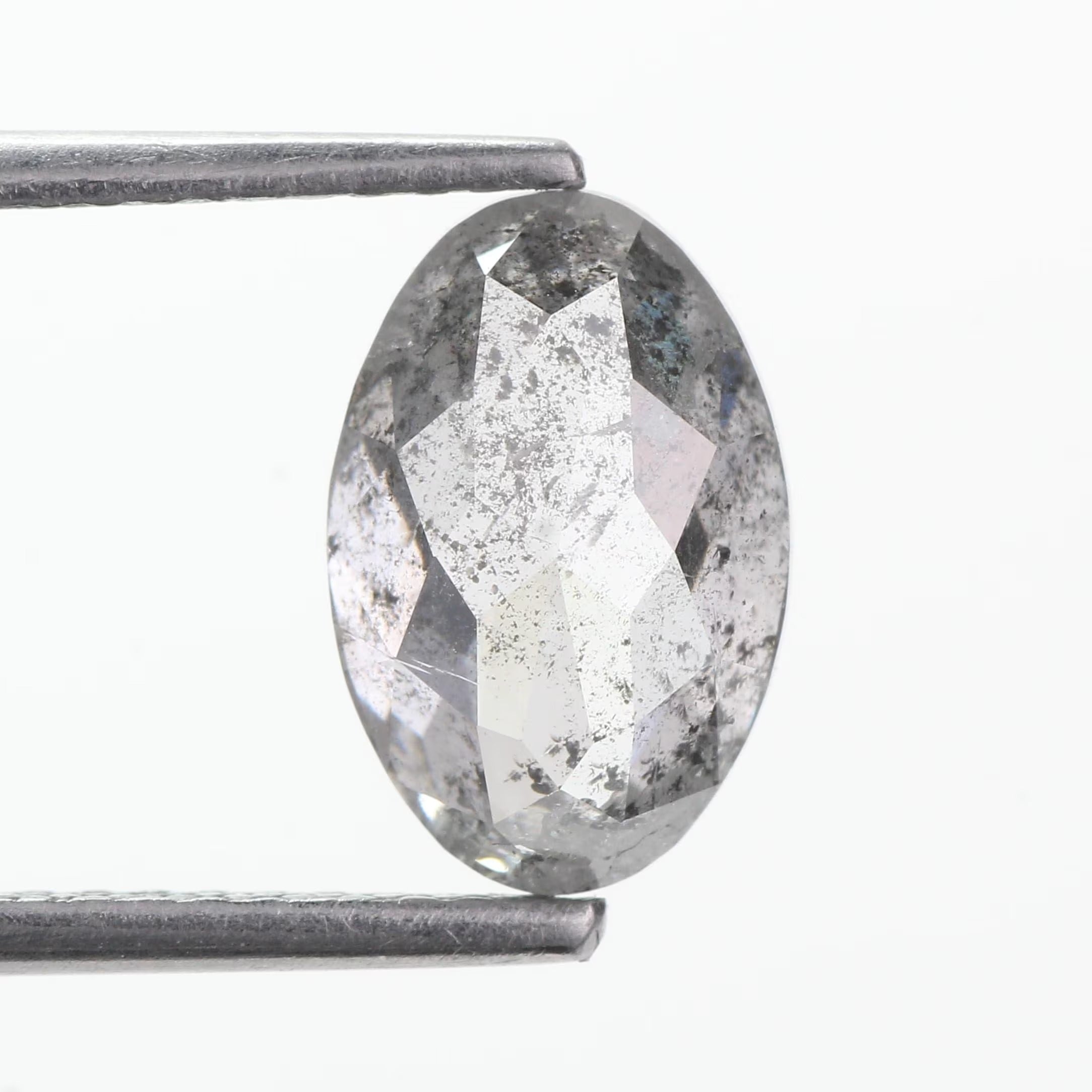 An oval-cut clear diamond with visible internal inclusions, held between metal tweezers against a plain white background.