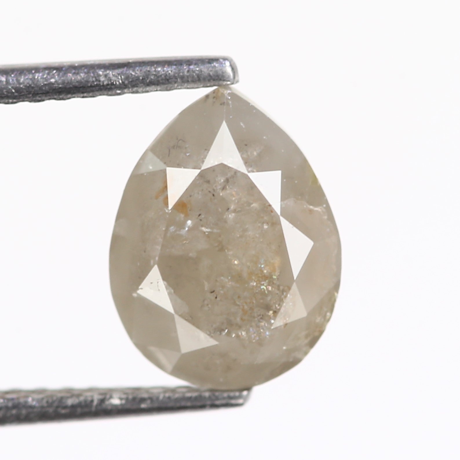 Pear-shaped diamond held by tweezers on a white background