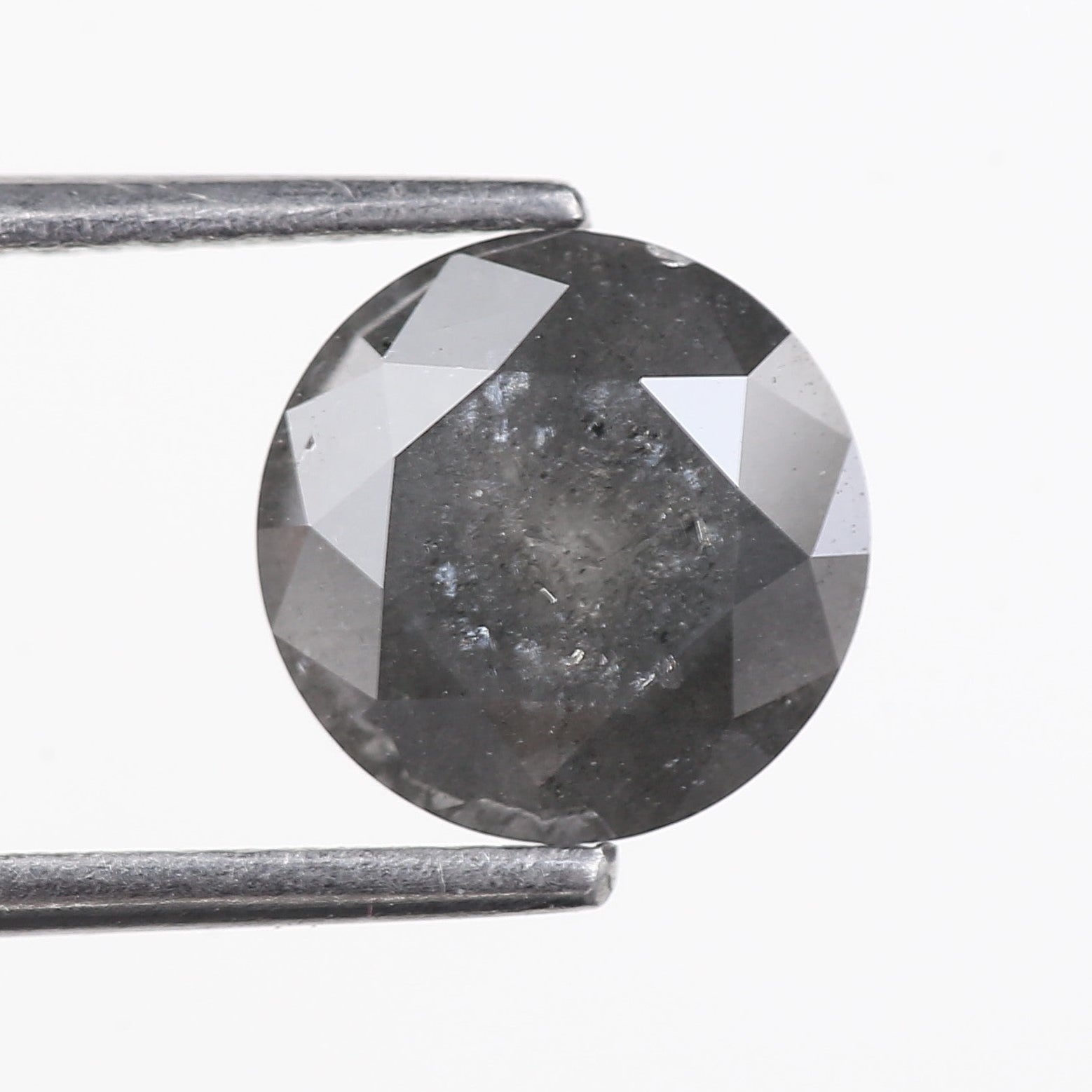 Faceted gray gemstone held between tweezers on a white background