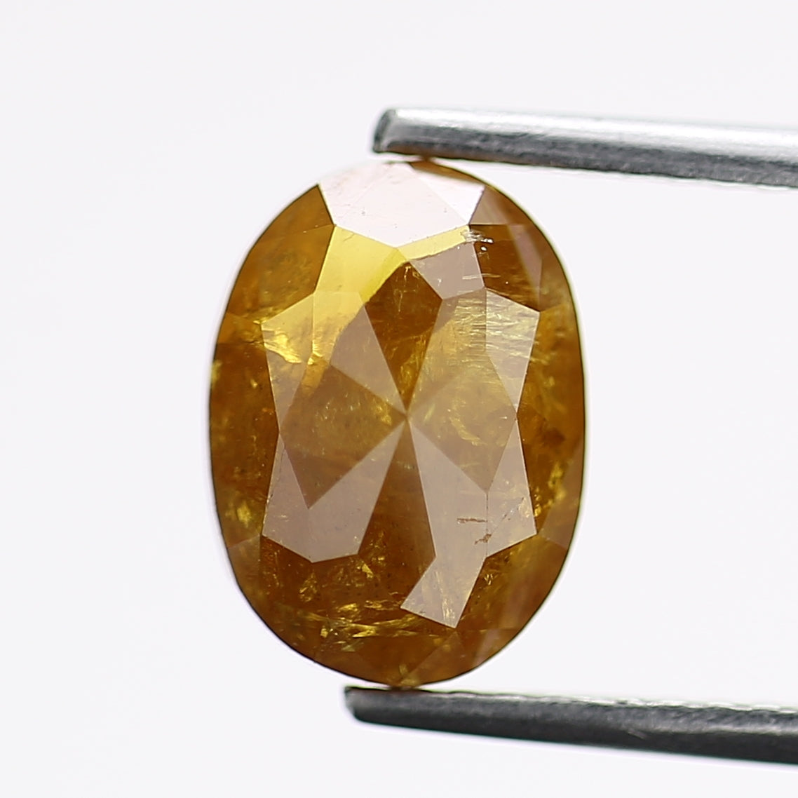 Faceted yellow gemstone held by tweezers on a white background