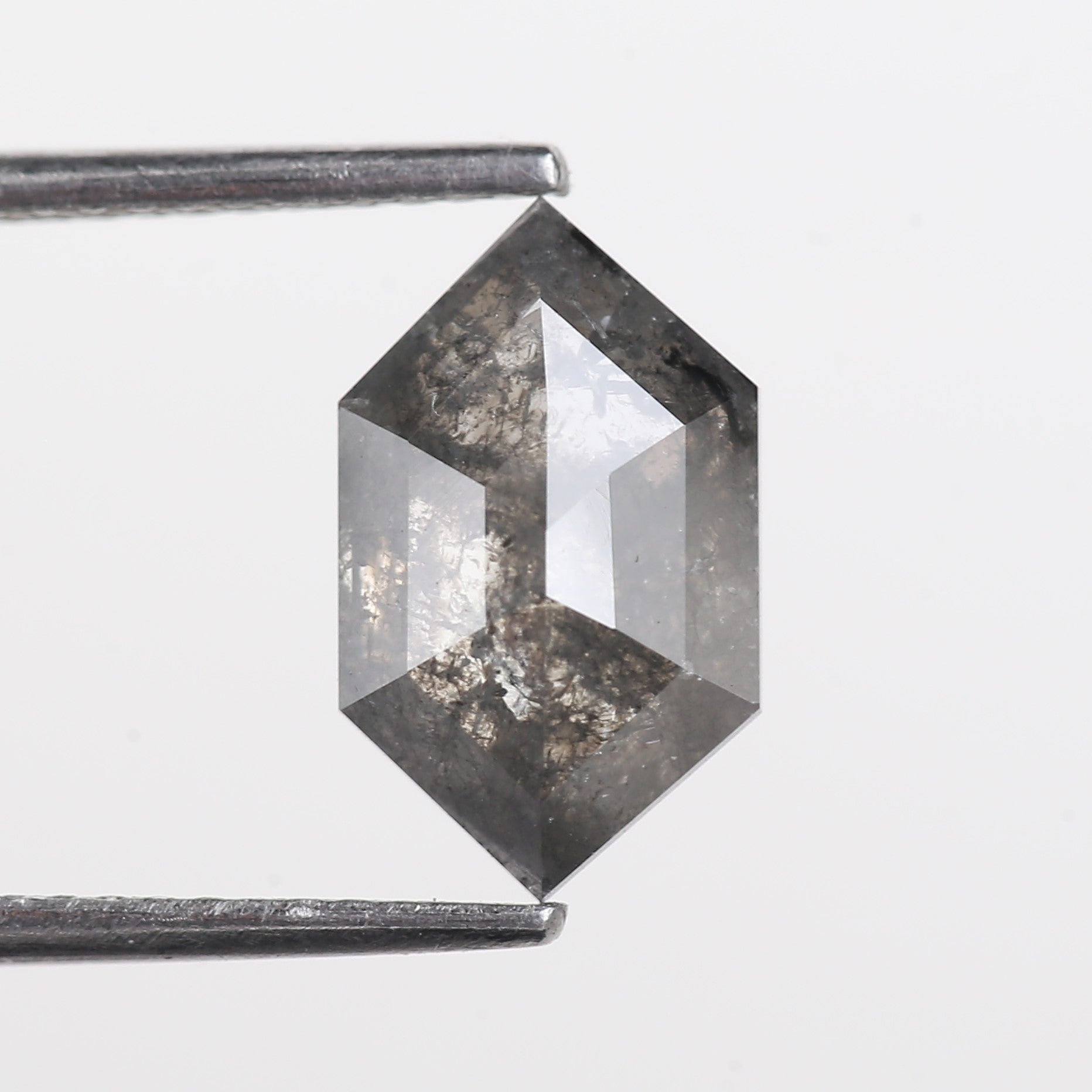 Hexagonal crystal held by tweezers on a light gray background