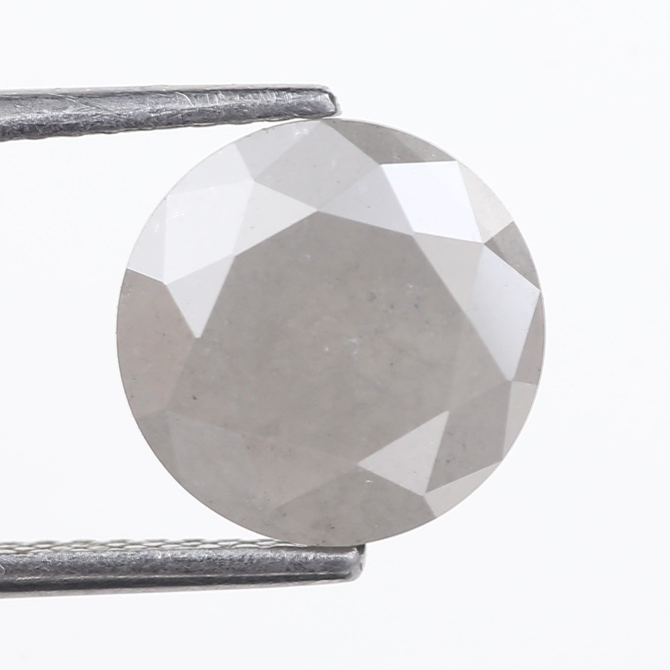 Clear gemstone held between tweezers on a white background