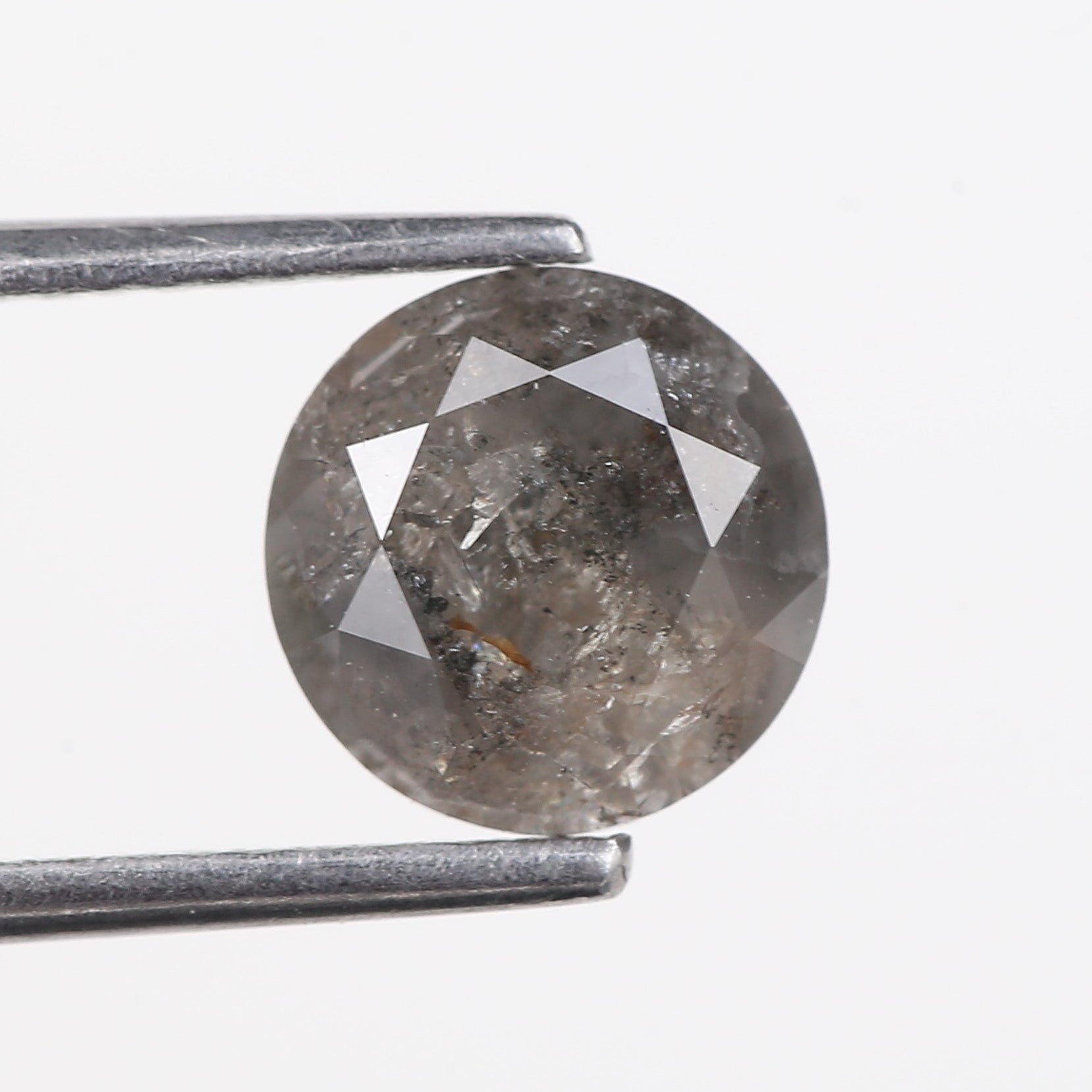 Round diamond held between tweezers on a white background