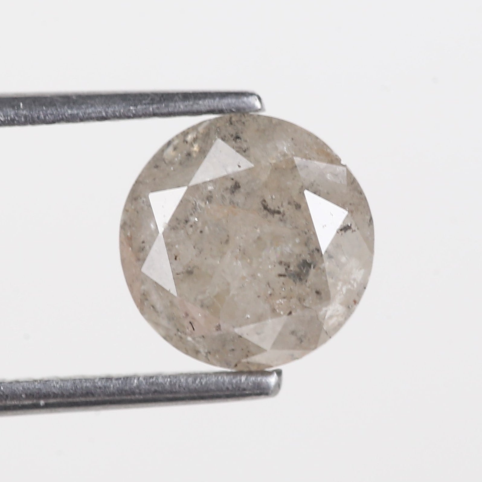 Diamond held by tweezers on a light gray background