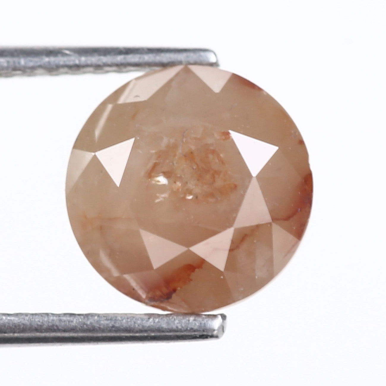 Round brown gemstone held by tweezers on a white background