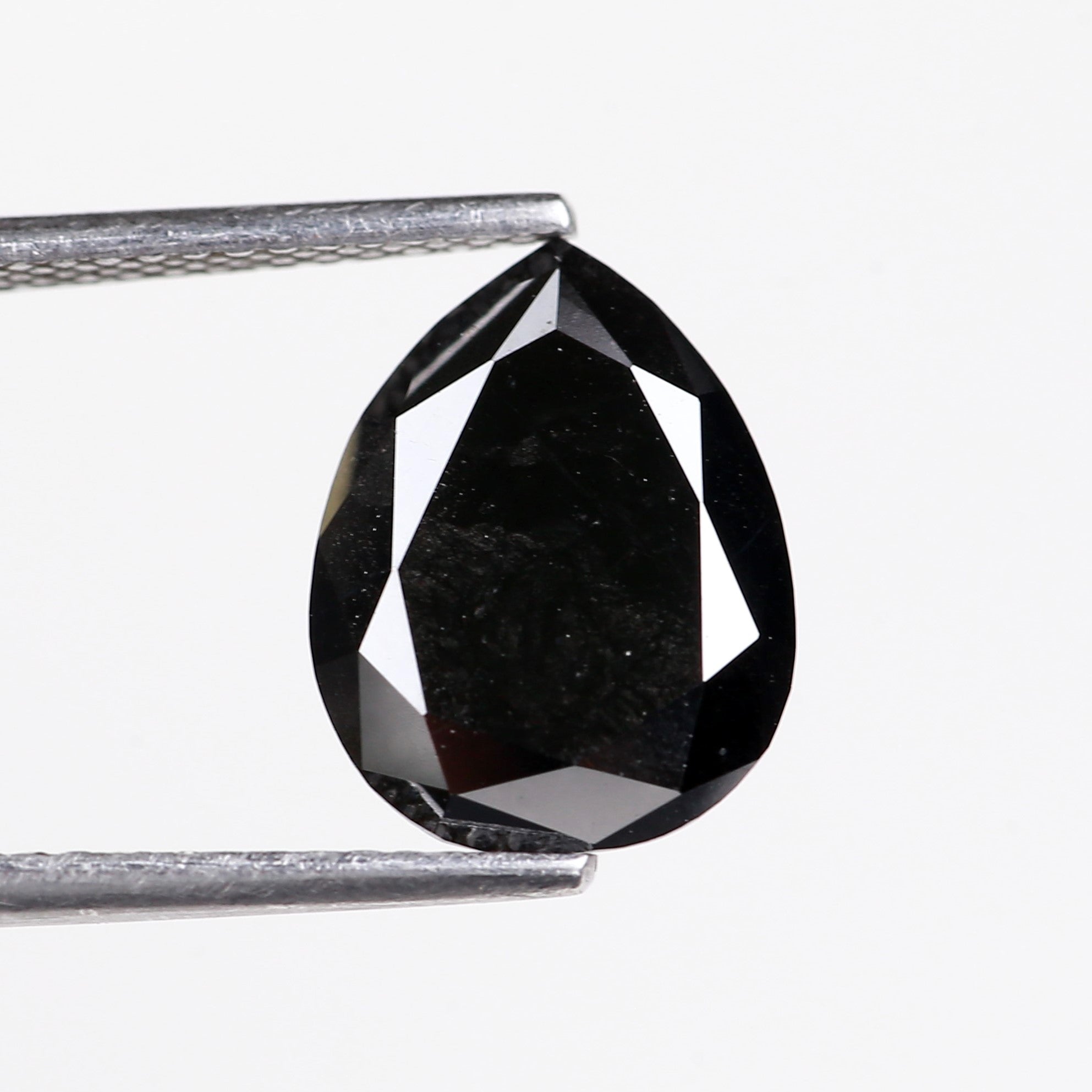 Black diamond held between two tweezers on a white background