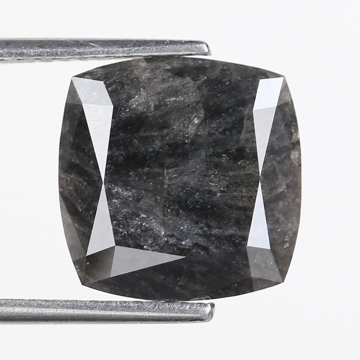 Gray cushion-cut gemstone held by tweezers on a white background