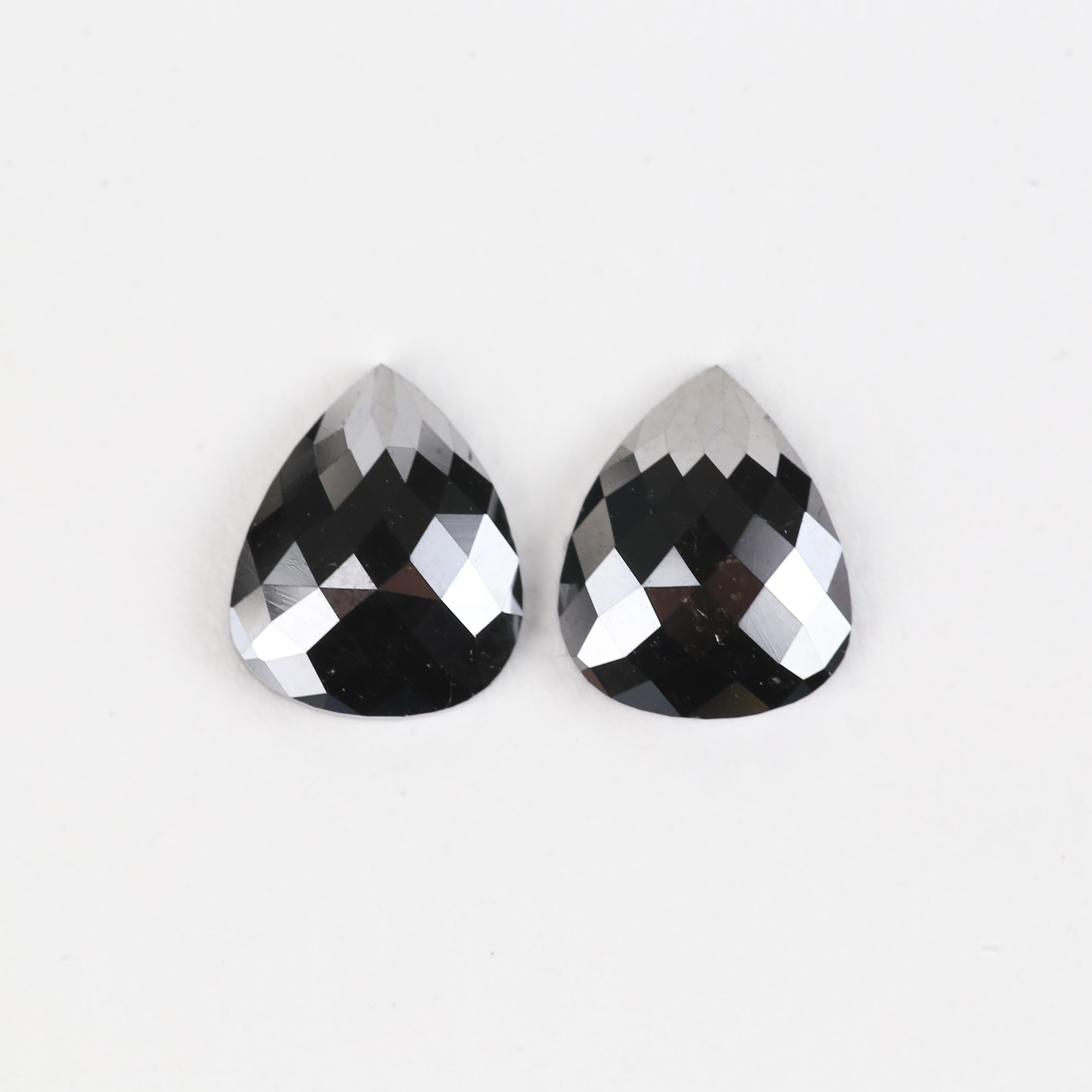 Two teardrop-shaped black gemstones on a white background