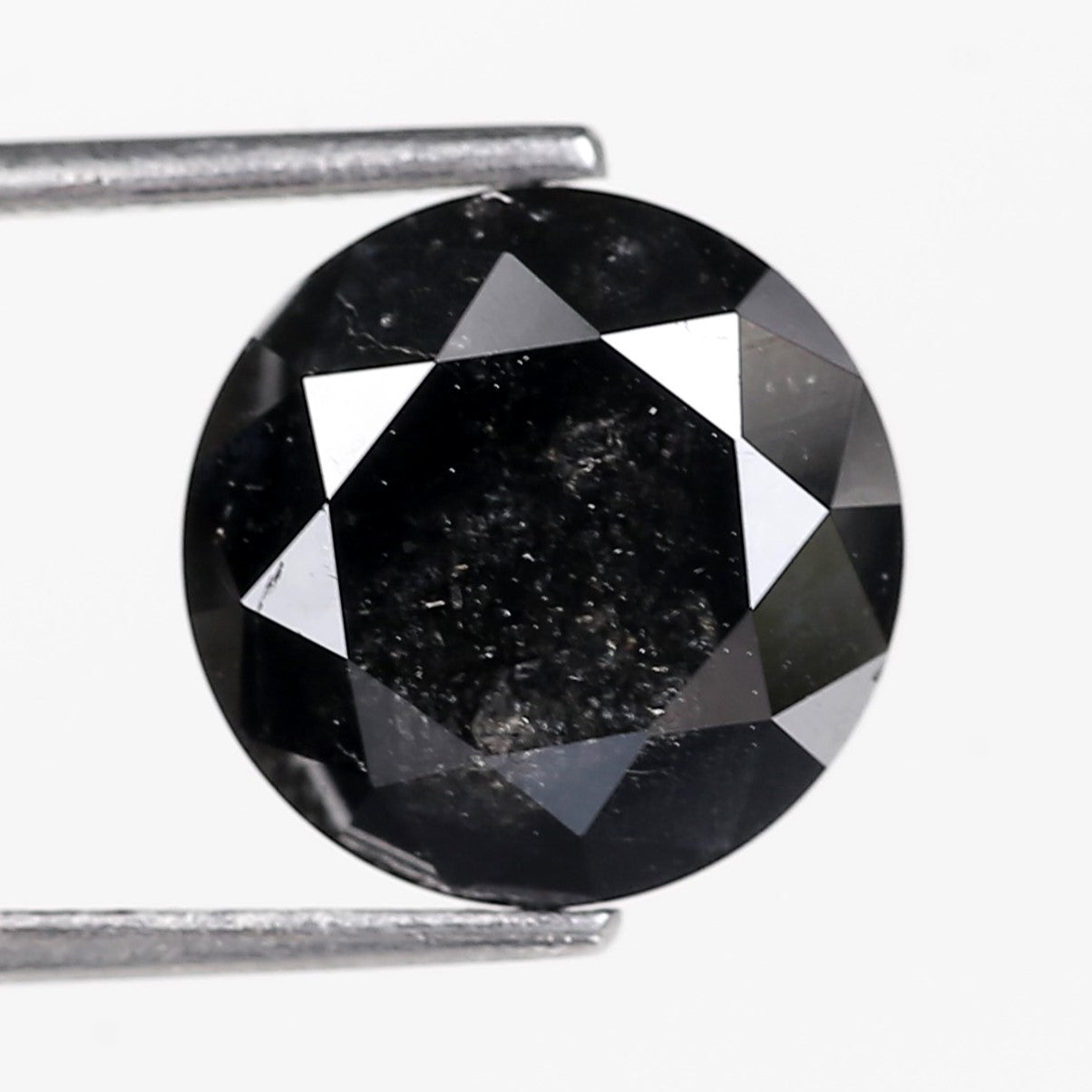Round black diamond held by tweezers on a white background