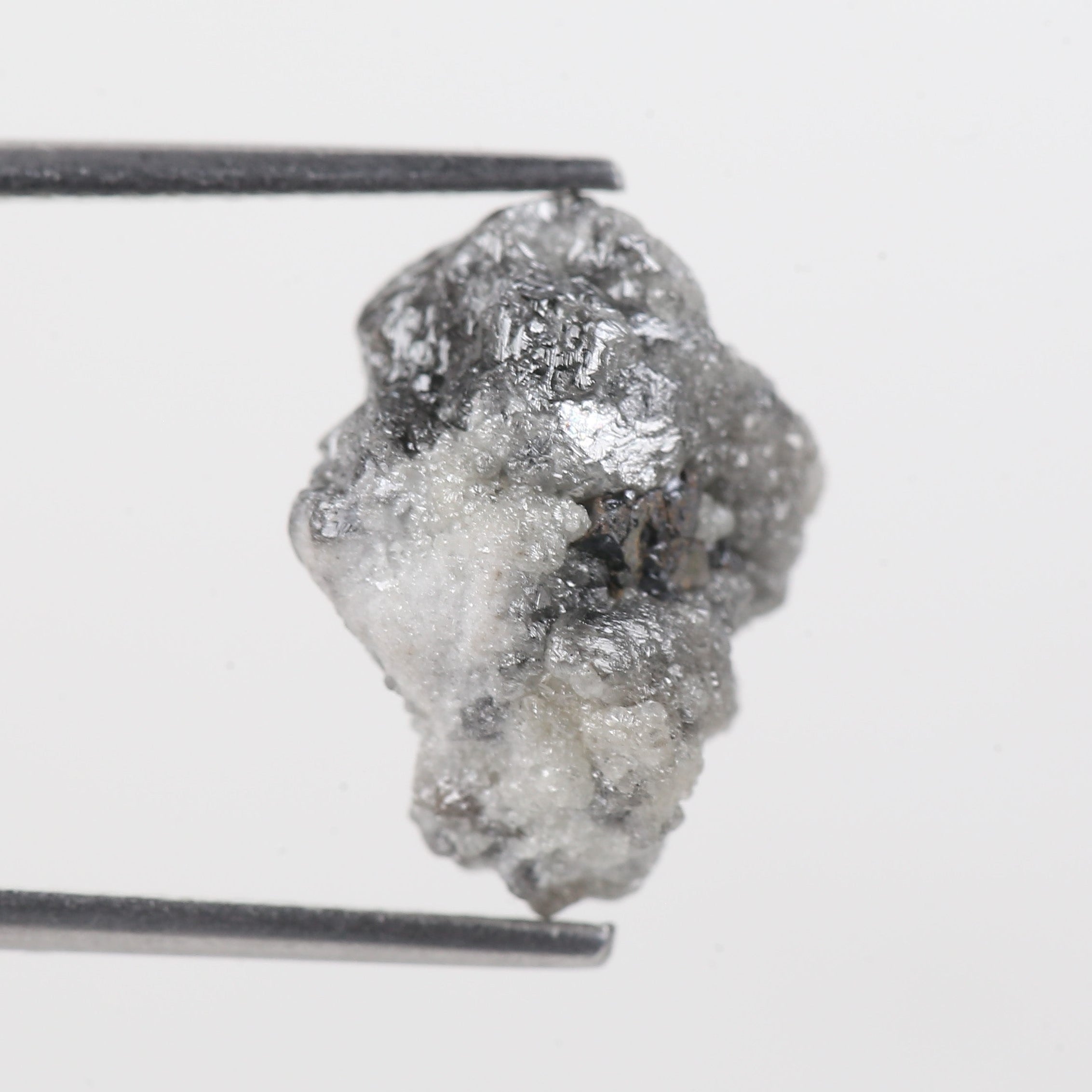 Raw diamond on a metal stand against a white background